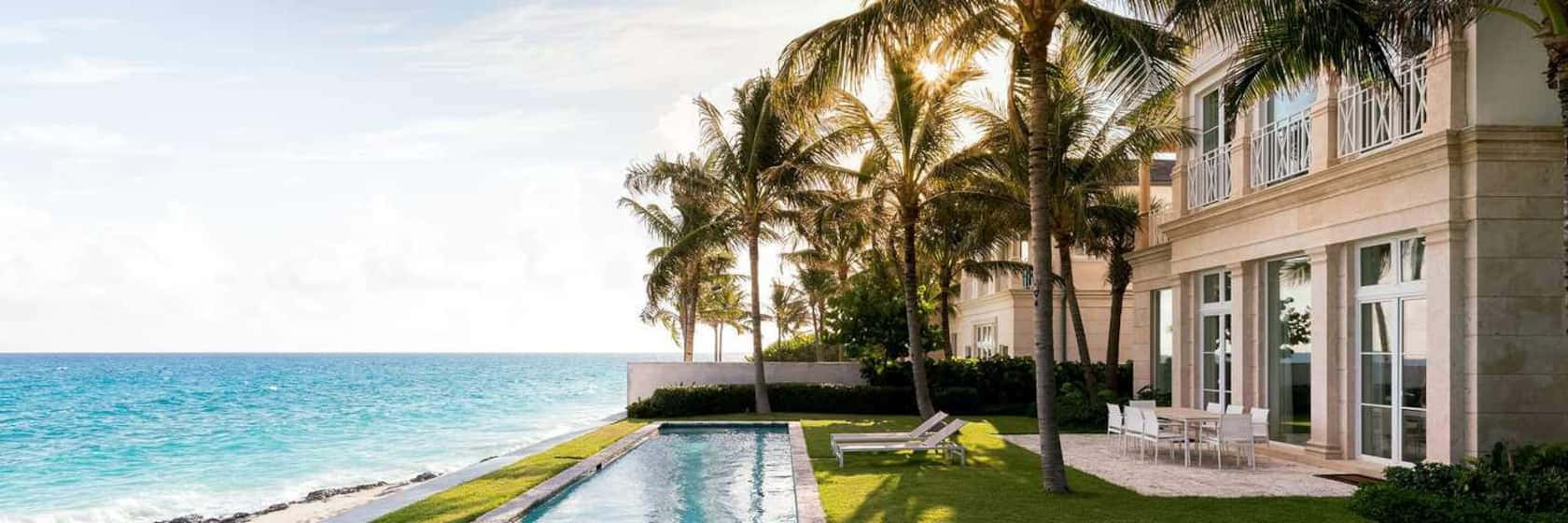 Bahamas Island 桌布 壁紙 — 豪華海濱別墅，設有無邊際泳池、棕櫚樹，在燦爛陽光下俯瞰碧綠海洋。