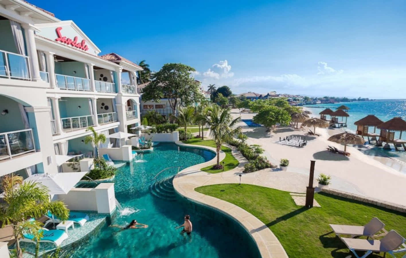 Jamaica 桌布 壁紙 — 豪華海濱度假村，擁有碧綠色的泳池蜿蜒穿過修剪整齊的草坪，在清澈的藍天下通往海洋。