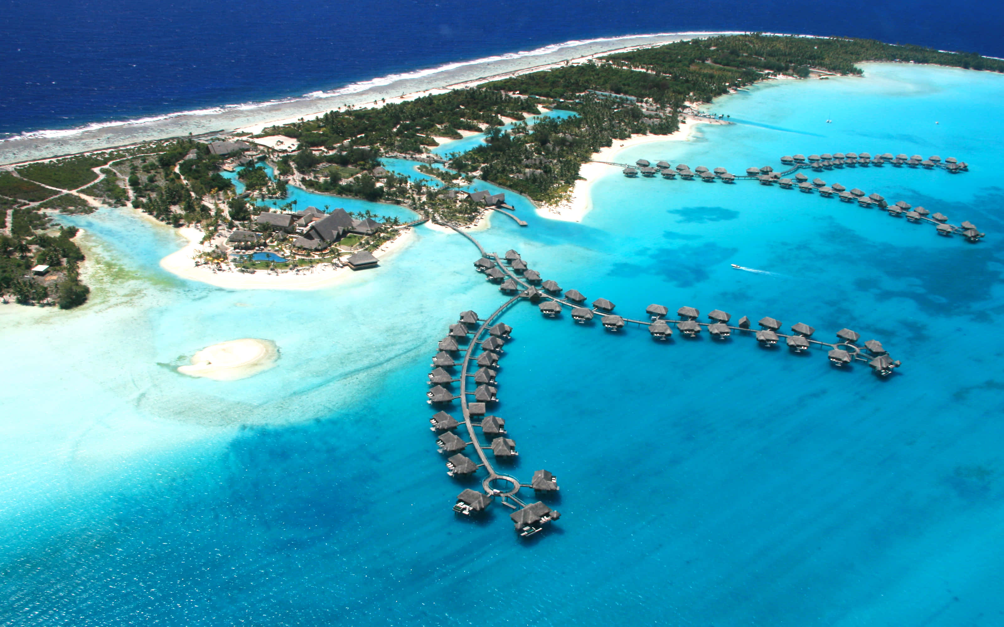 Bora Bora Beach 桌布 壁紙 — 豪華熱帶島嶼度假村的鳥瞰圖，水上平房延伸至充滿活力的碧綠潟湖水域。