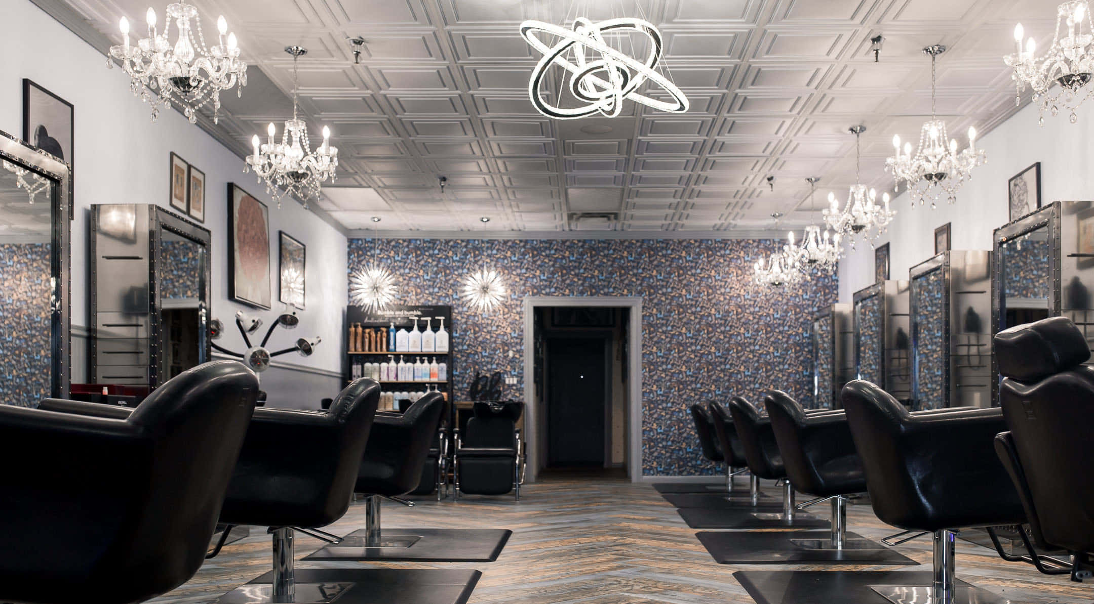 Hair Salon 桌布 壁紙 — 豪華現代髮廊，設有黑色皮革椅、鍍鉻鏡子和方格天花板下閃爍的水晶吊燈。