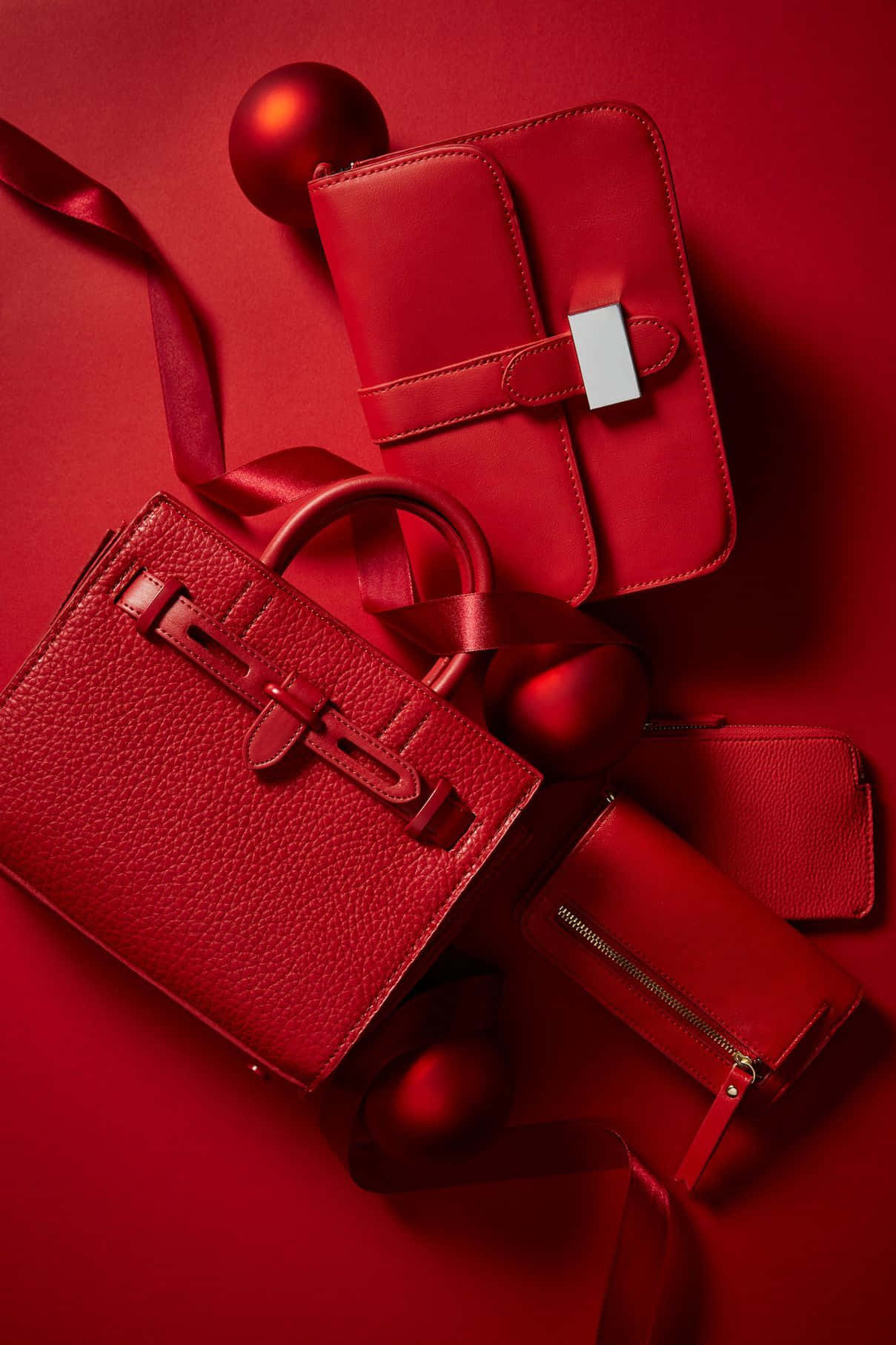 Red Handbag 桌布 壁紙 — 豪華紅色皮革手袋及配件，配以緞帶和裝飾品，優雅地陳列在濃郁的紅色背景上。