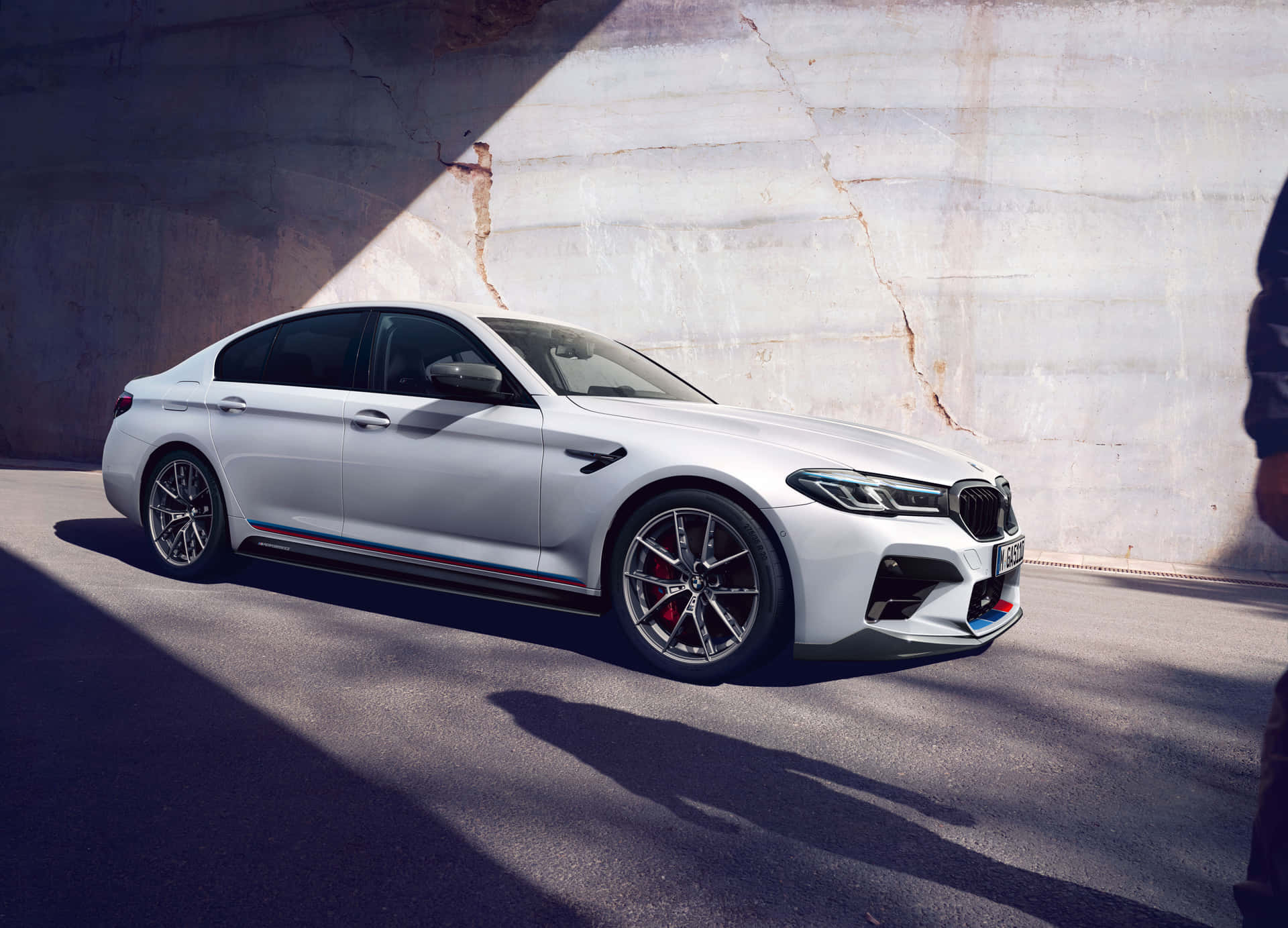 白色BMW M5停泊在混凝土天橋下，帶有強烈陰影。