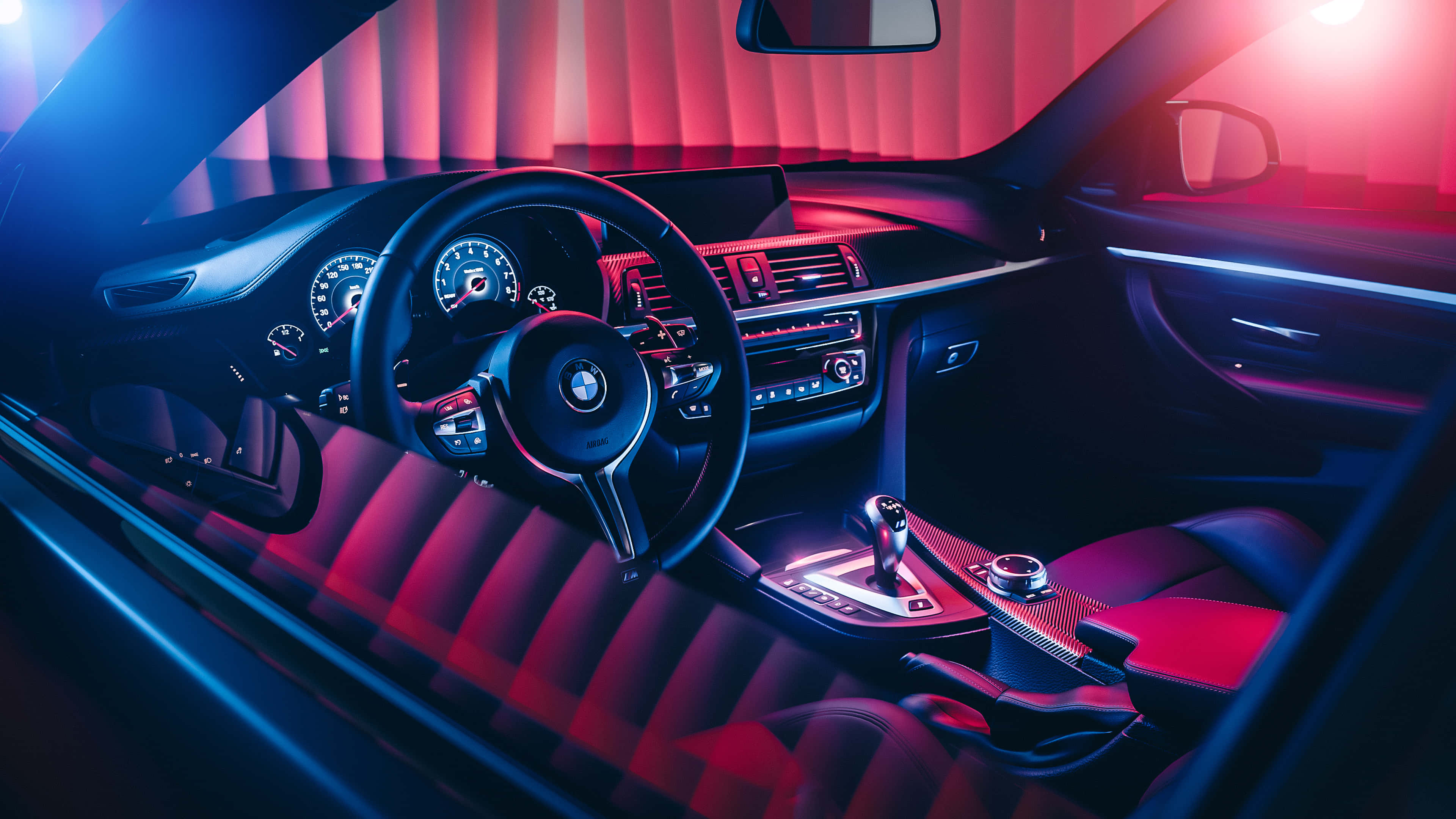 4K BMW 壁紙 桌布 壁紙 — 豪華車內籠沐浴在鮮豔的紅色和藍色霓虹燈光下，突顯時尚的儀表板和運動座椅。