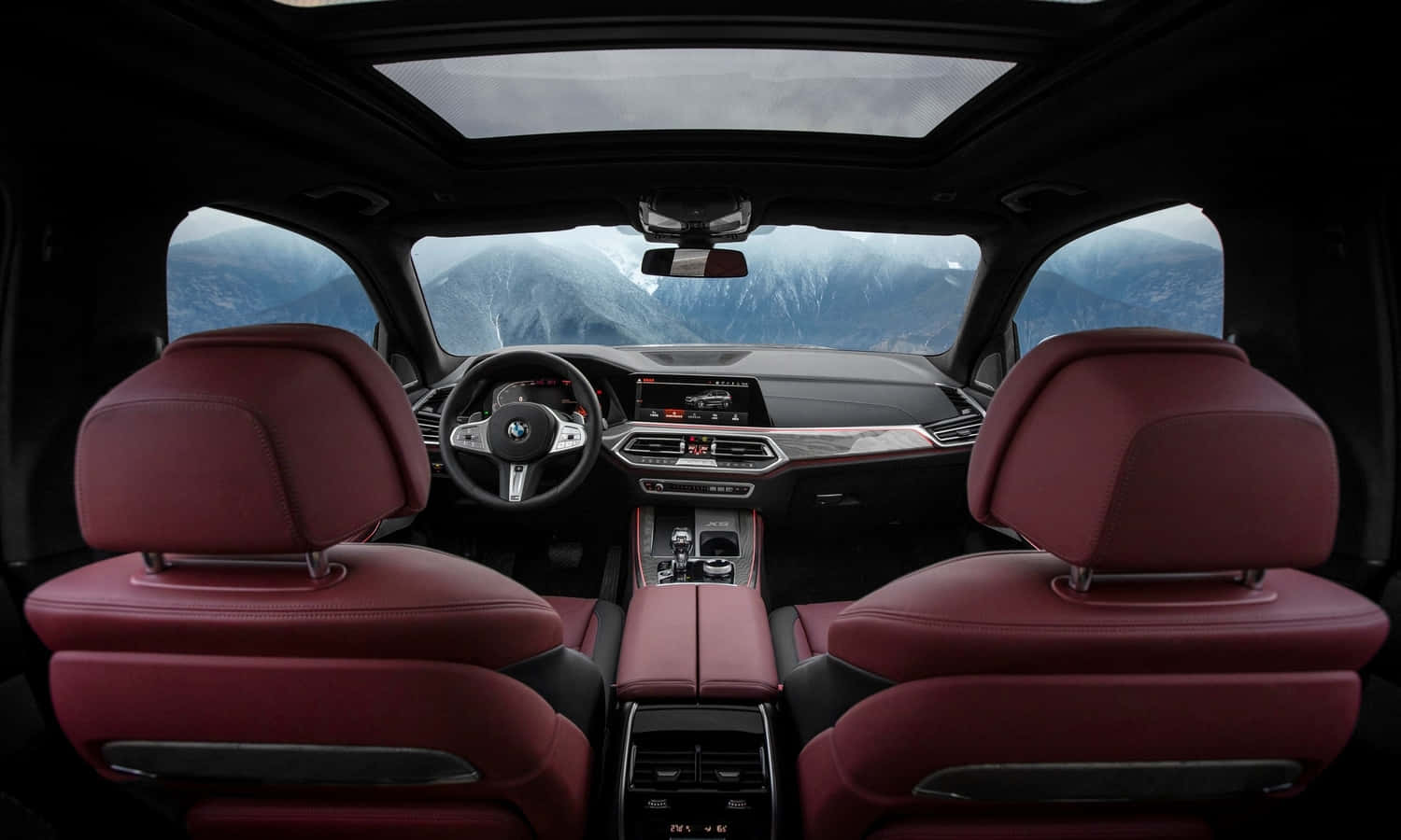 Bmw X5 桌布 壁紙 — 豪華車內飾，配備紅色皮革座椅，透過全景玻璃車頂欣賞山景。