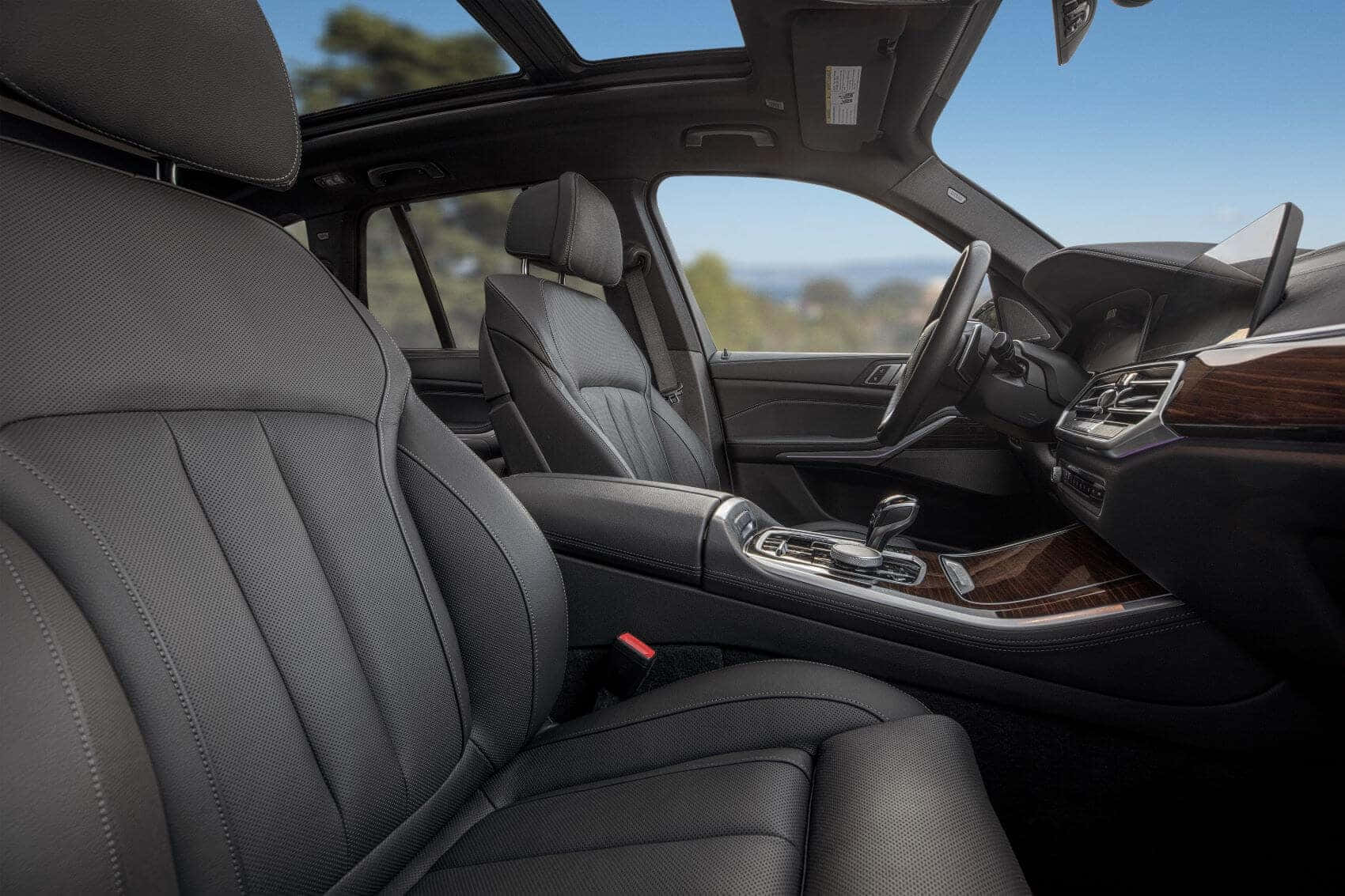 Bmw X5 桌布 壁紙 — 豪華車內飾，配備黑色皮革座椅和木質飾邊，在明亮的日光下展現頂級工藝。