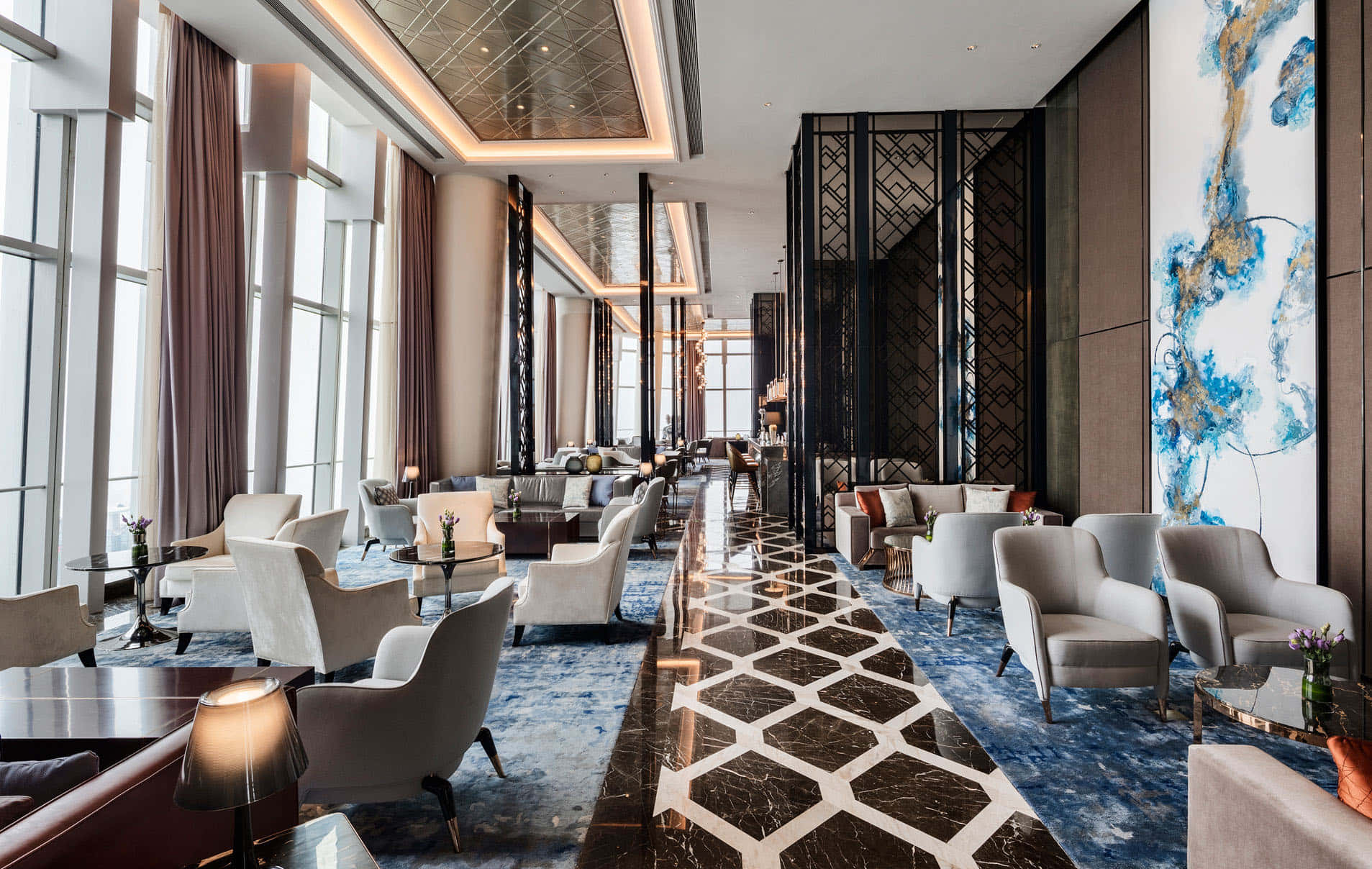 Interior Design 桌布 壁紙 — 豪華酒店大堂，舖有大理石地板、幾何圖案、豪華座椅，以及讓自然光灑滿空間的大型窗戶。