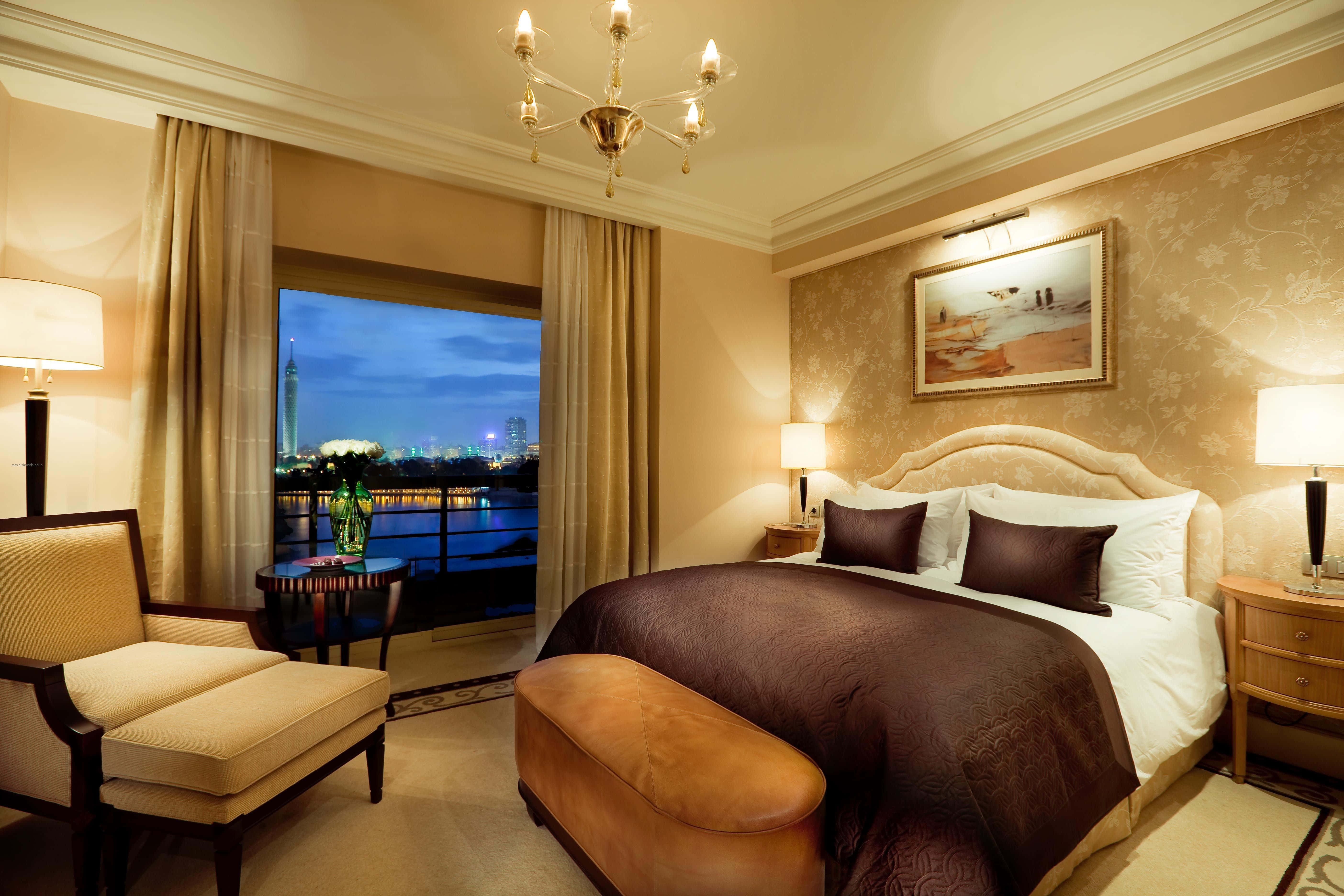 Hotel Room 桌布 壁紙 — 豪華酒店睡房，配備優雅家具，可欣賞黃昏時分的城市景觀。