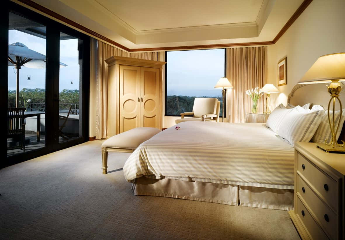 Hotel Room 桌布 壁紙 — 豪華酒店睡房，配備大床、溫暖燈光，透過玻璃門可欣賞綠意景觀。