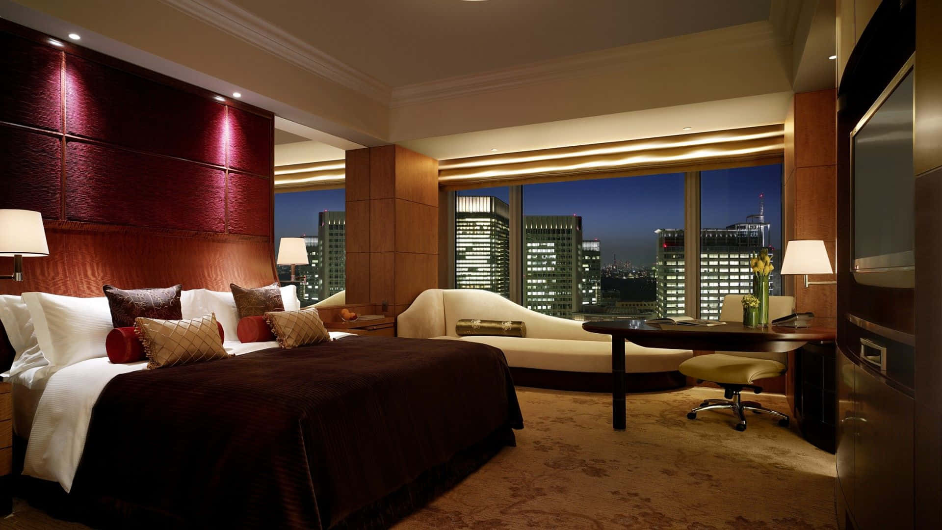 Hotel Room 桌布 壁紙 — 豪華酒店臥室，配有深紅色床頭板和夜晚的城市天際線景觀。