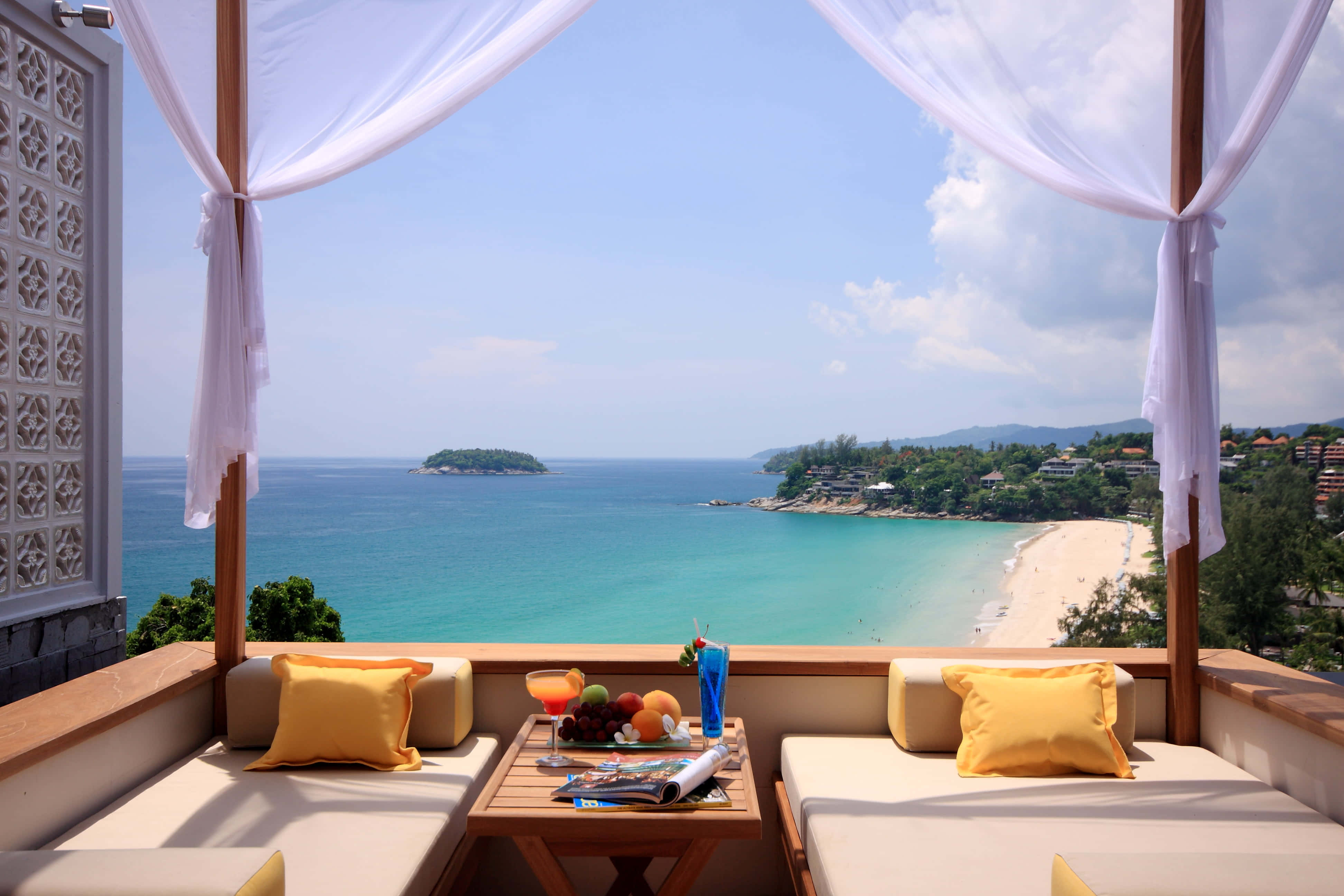 Beach Daybed 桌布 壁紙 — 豪華陽台配有白色窗簾，俯瞰湛藍海洋和沙灘，天空明亮湛藍。