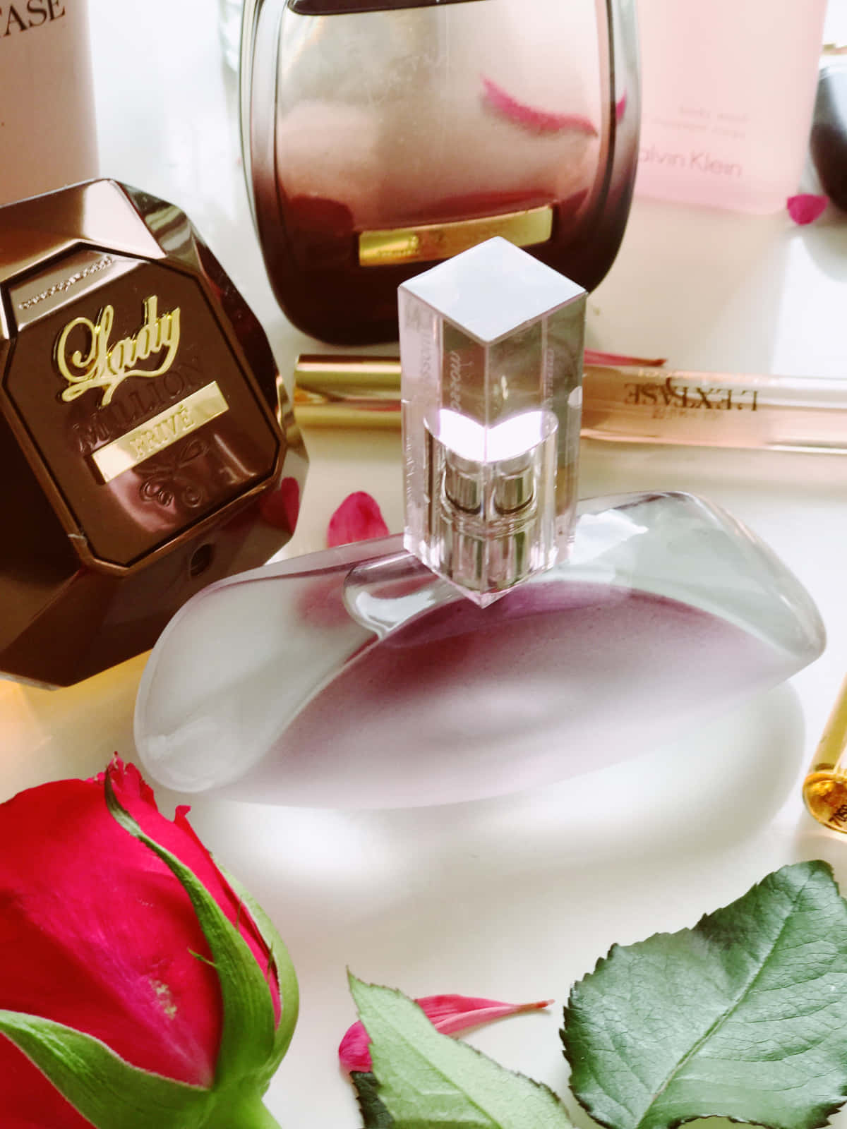 Spring Perfume 桌布 壁紙 — 豪華香水瓶和一朵紅玫瑰花蕾在明亮的白色表面上特寫。