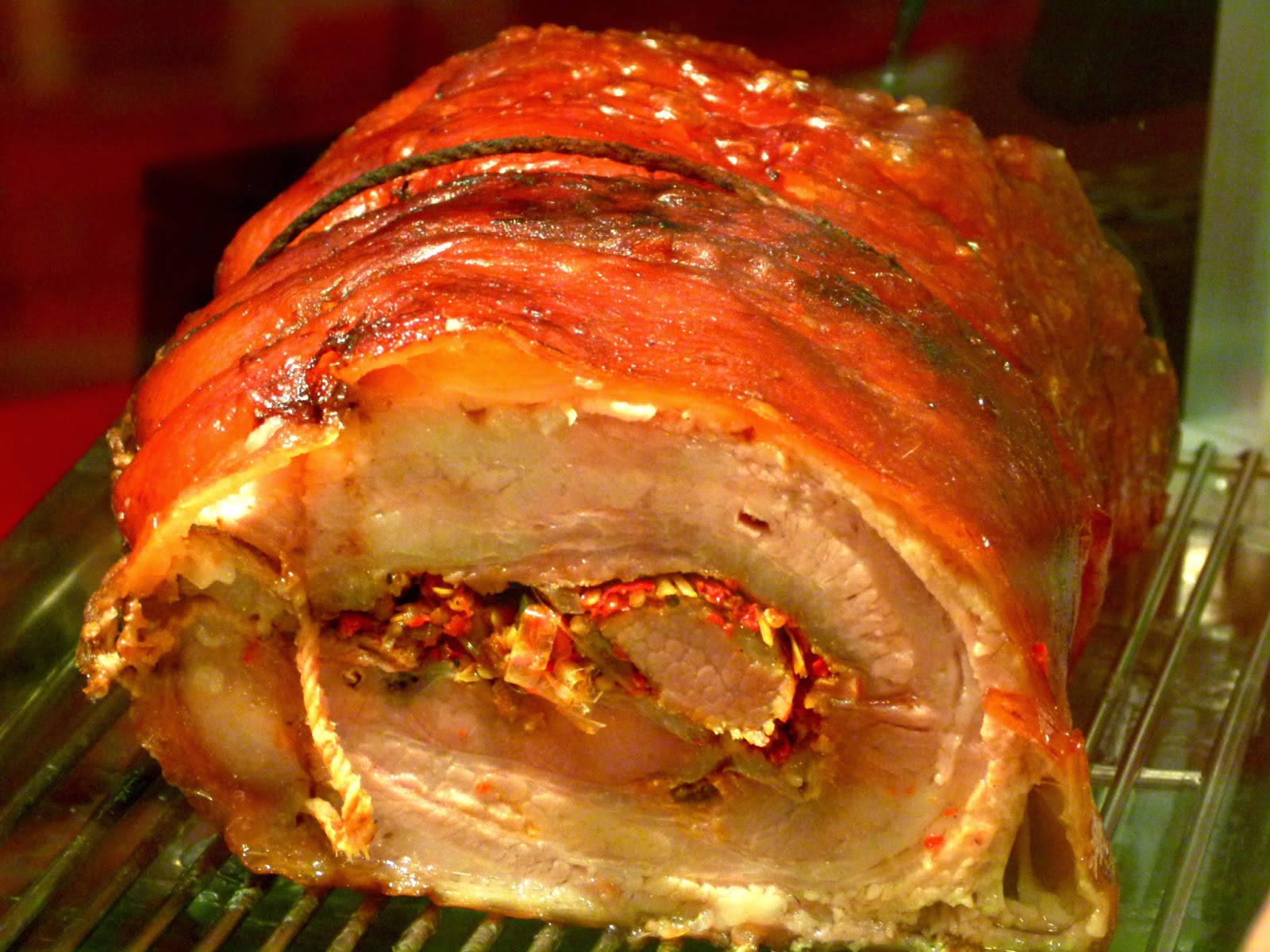 豬腩卷 壁紙 — 完美烤豬肉，帶有酥脆焦糖外皮和香草餡料，放在金屬架上。