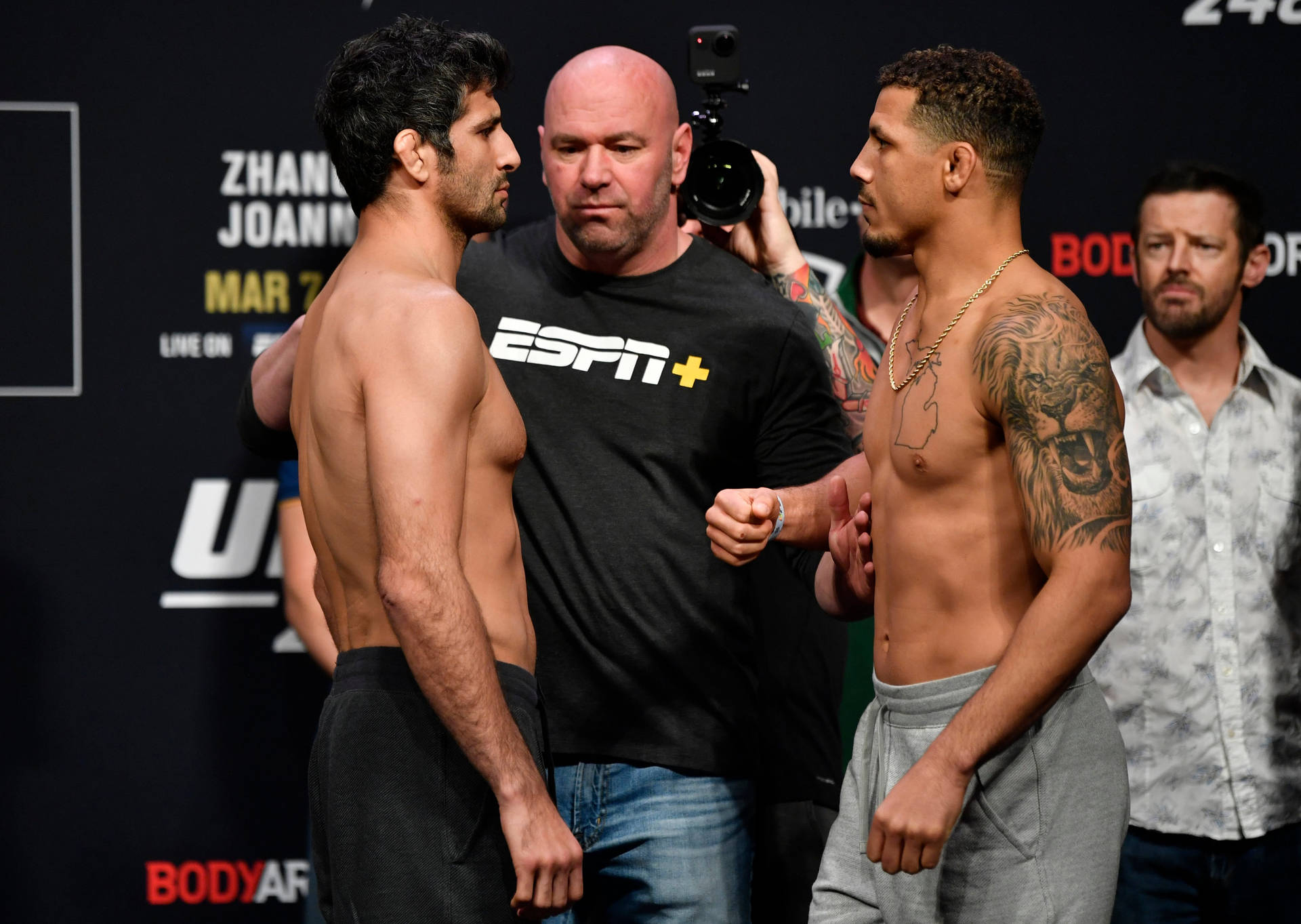 兩名男性MMA拳手在UFC稱重活動中與裁判和攝製組互相凝視。