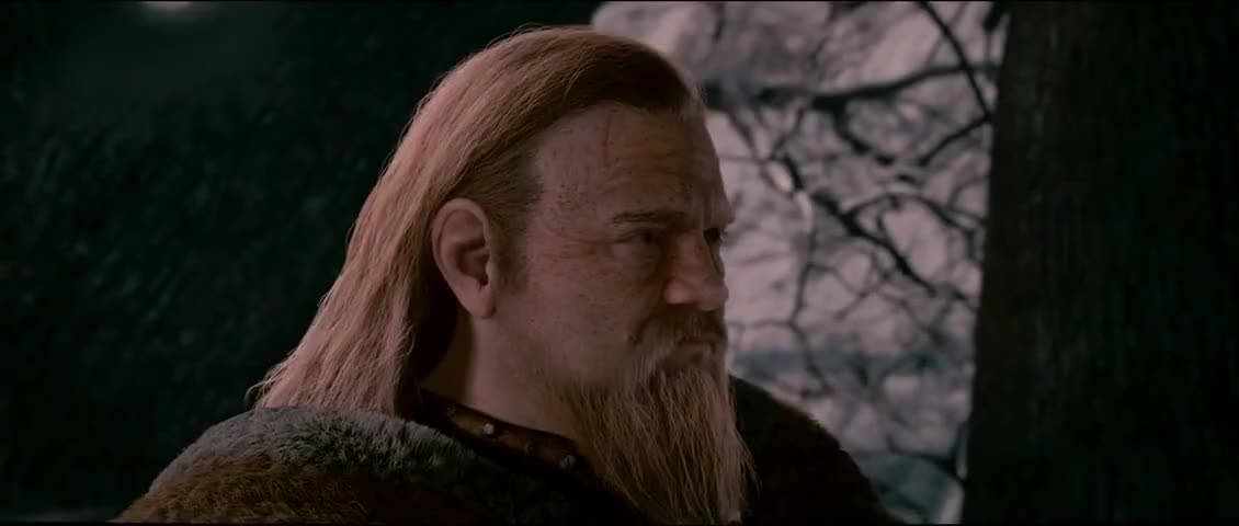 一個鬍鬚男人在黃昏時分的雪森林中穿著毛皮大衣。