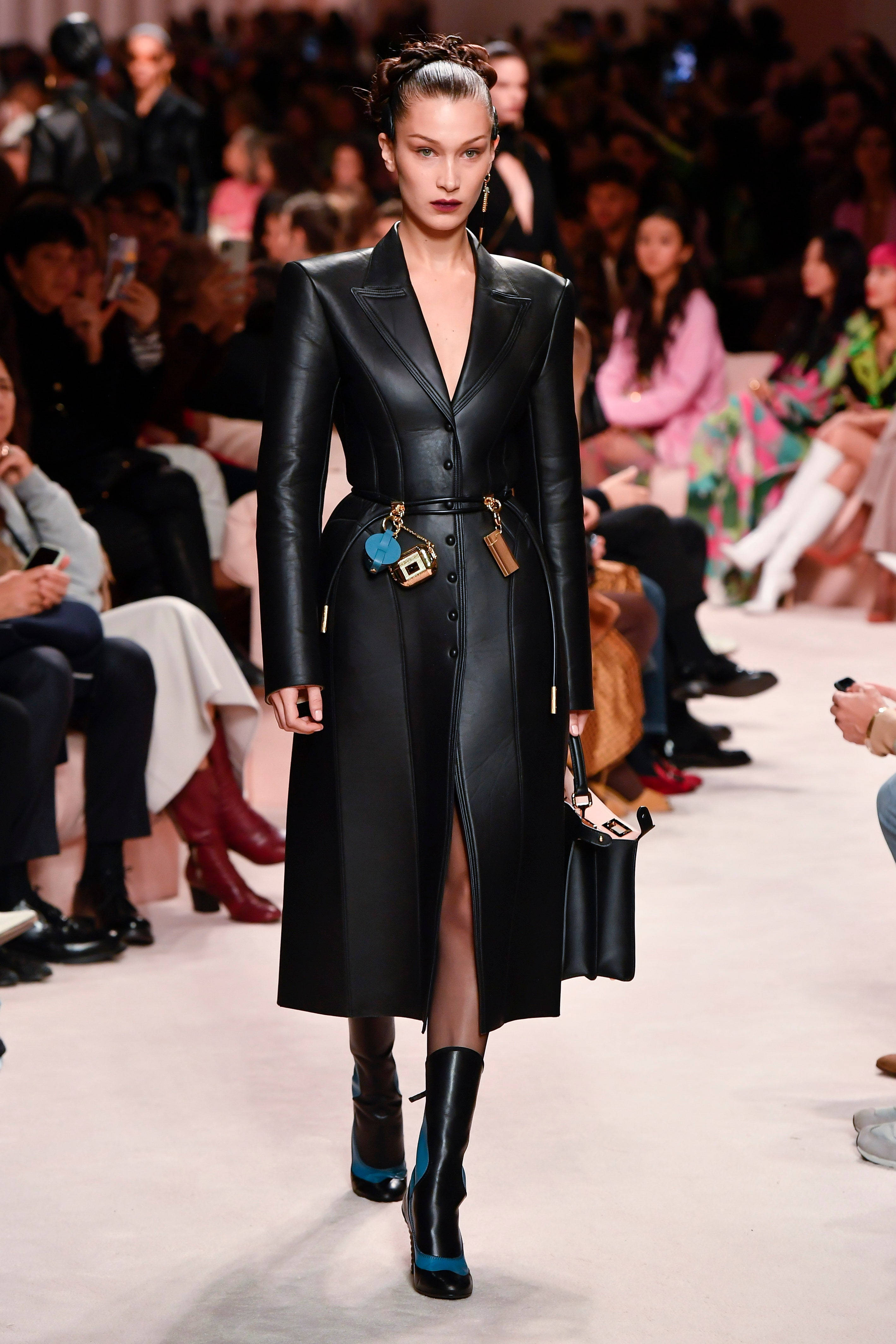 貝拉·哈迪德穿 Fendi 皮衣 壁紙 — 模特兒自信地走在天橋上，身穿時尚黑色皮革風衣，開衩高，靴子帶有搶眼的藍色點綴。