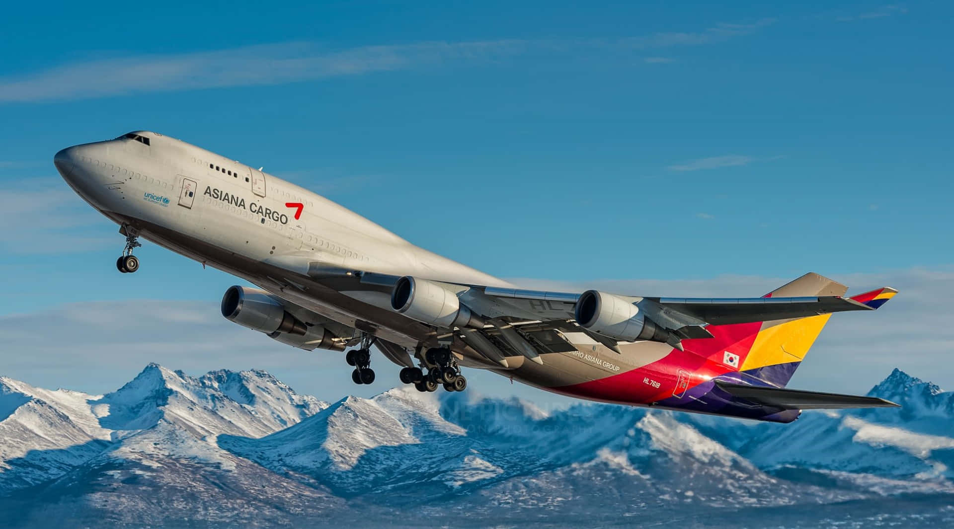 韓亞航空貨運波音747低飛越過積雪山脈，起落架伸出。