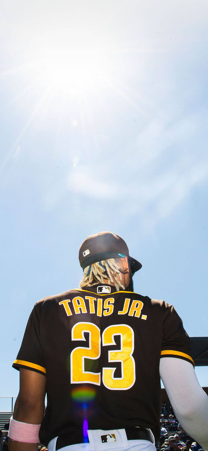 身穿黑色和黃色球衣的棒球手Tatis Jr站在燦爛陽光下。