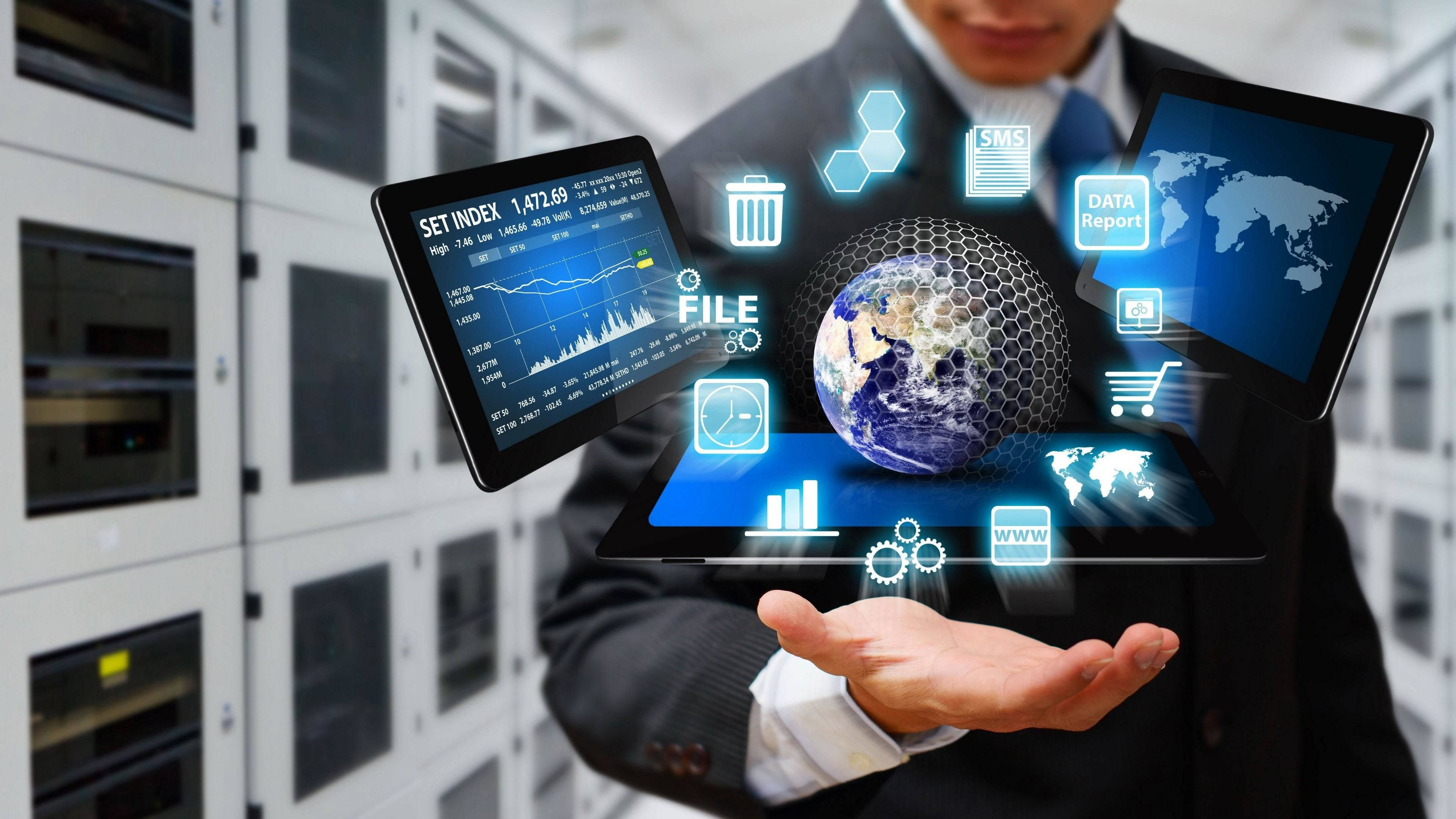 資訊科技混合解決方案 壁紙 — 一位商人在伺服器機房手持全息顯示屏，展示全球數據分析和數字圖標。