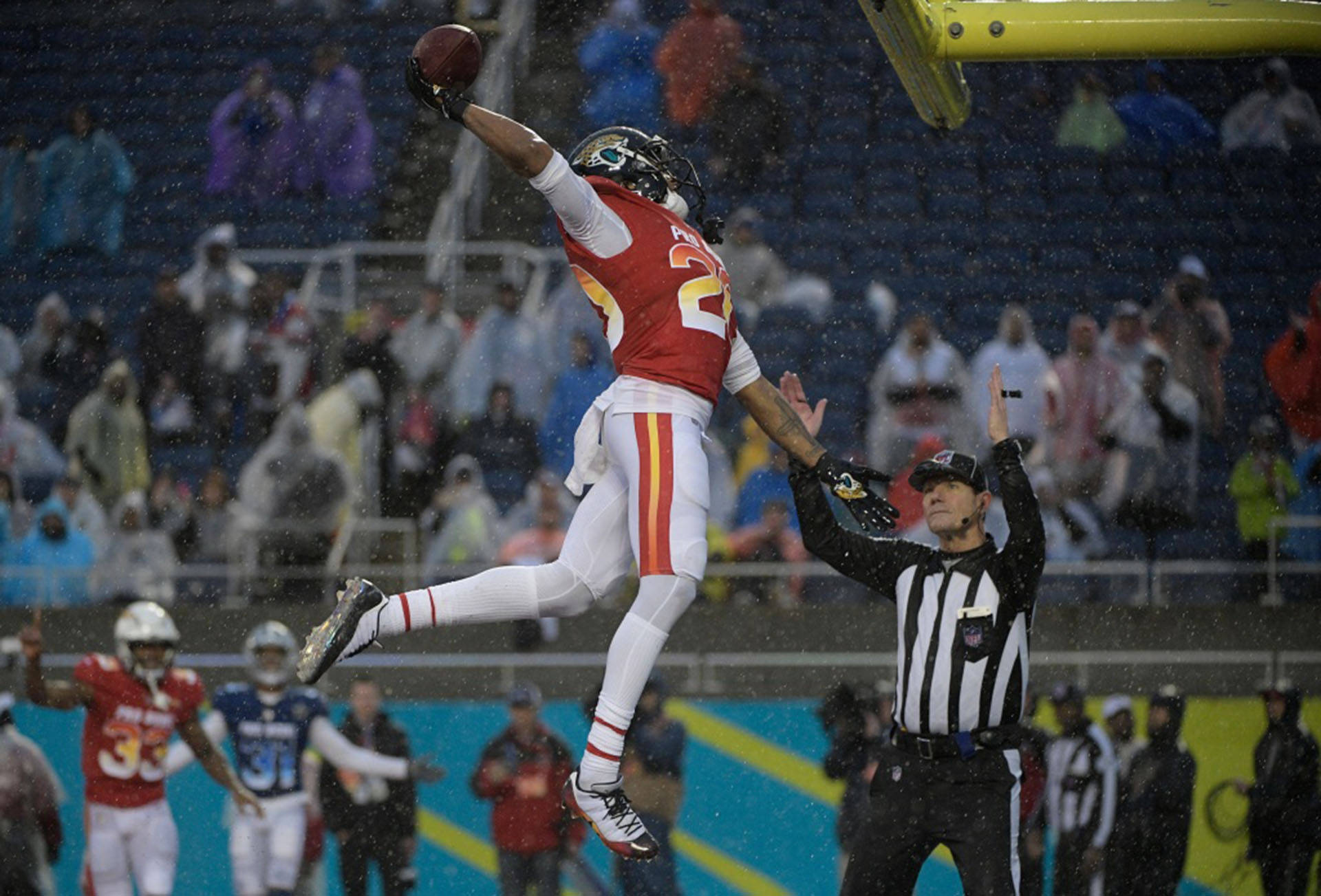 賈倫·拉姆西 NFL 職業碗踢球 壁紙 — 一名美式足球員在雨中高高躍起接住達陣傳球，下方裁判正在示意。