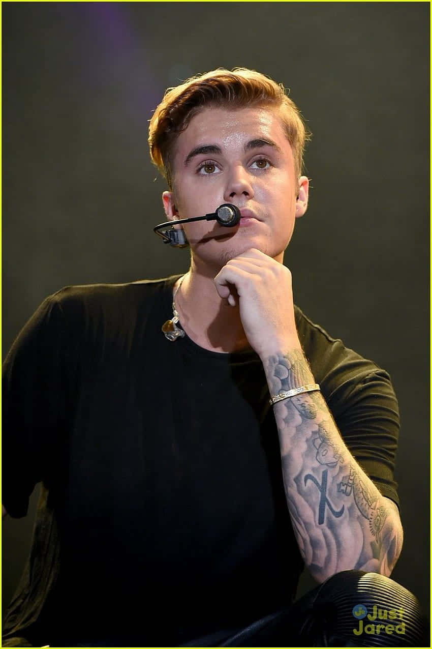 Justin Bieber 在舞台上表演，帶有紋身和耳機麥克風。