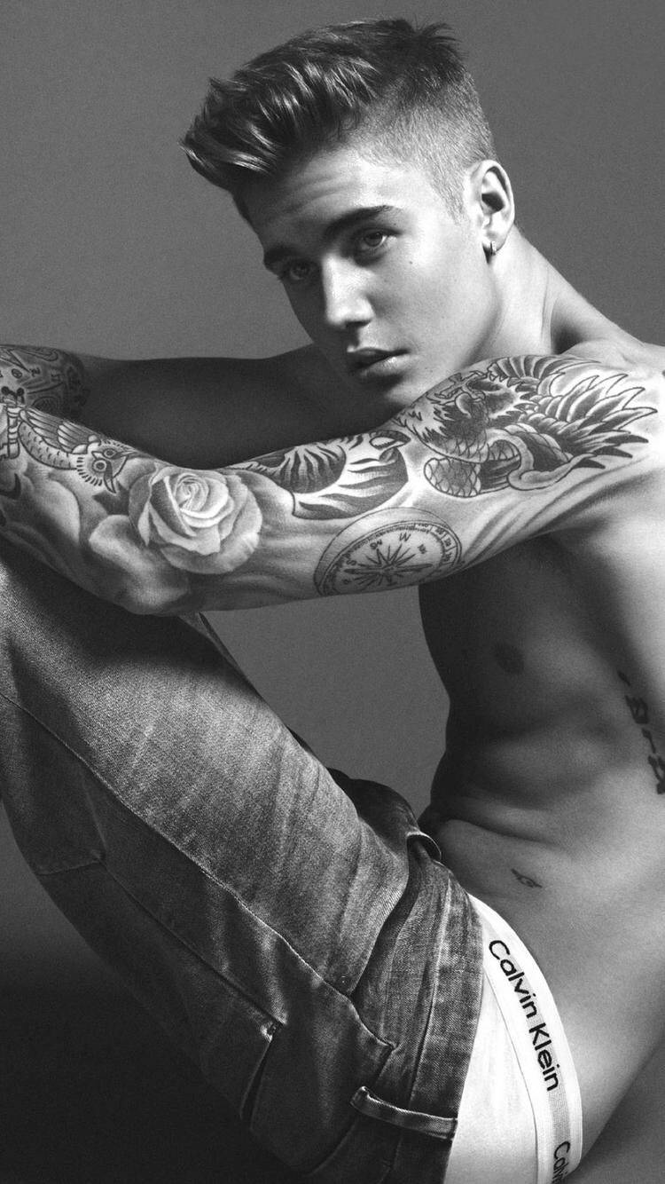 有紋身的年輕男子穿著牛仔褲和Calvin Klein內褲擺姿勢。
