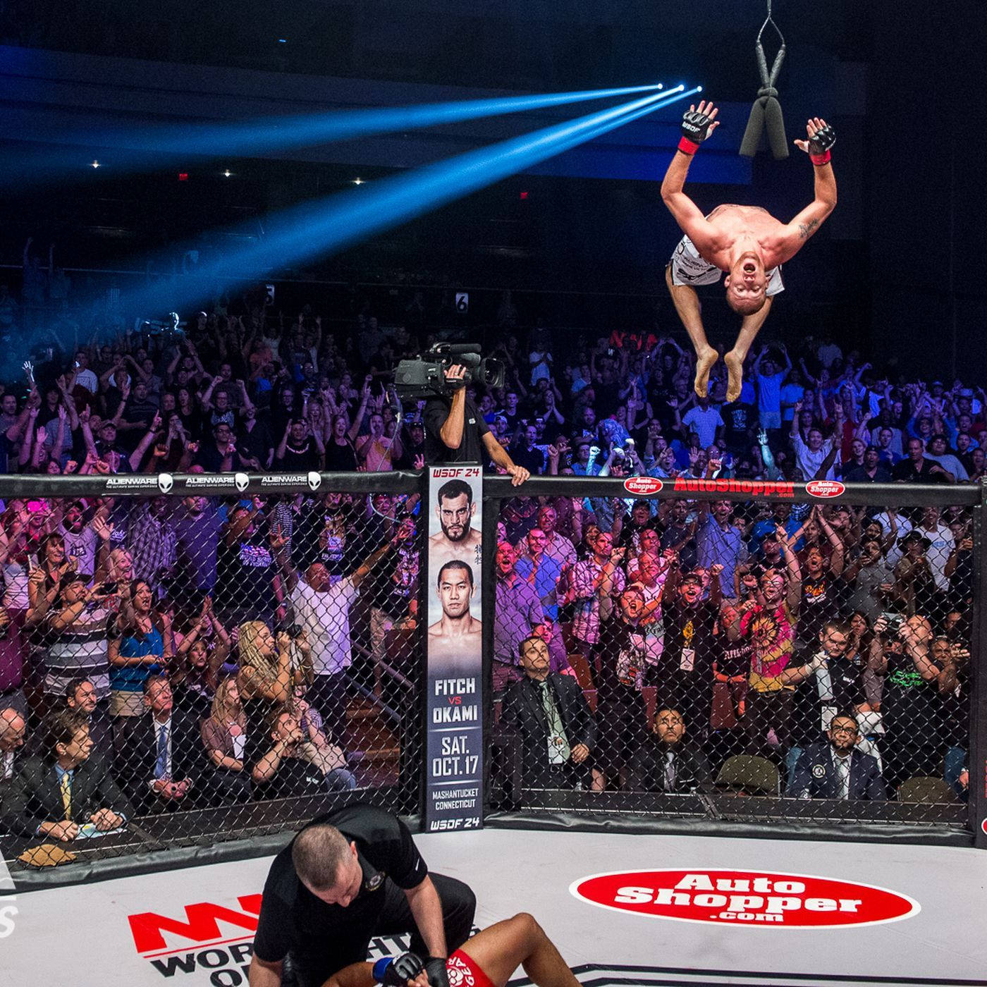 MMA拳手倒掛在八角籠天花板上慶祝勝利，對手則敗倒在地。