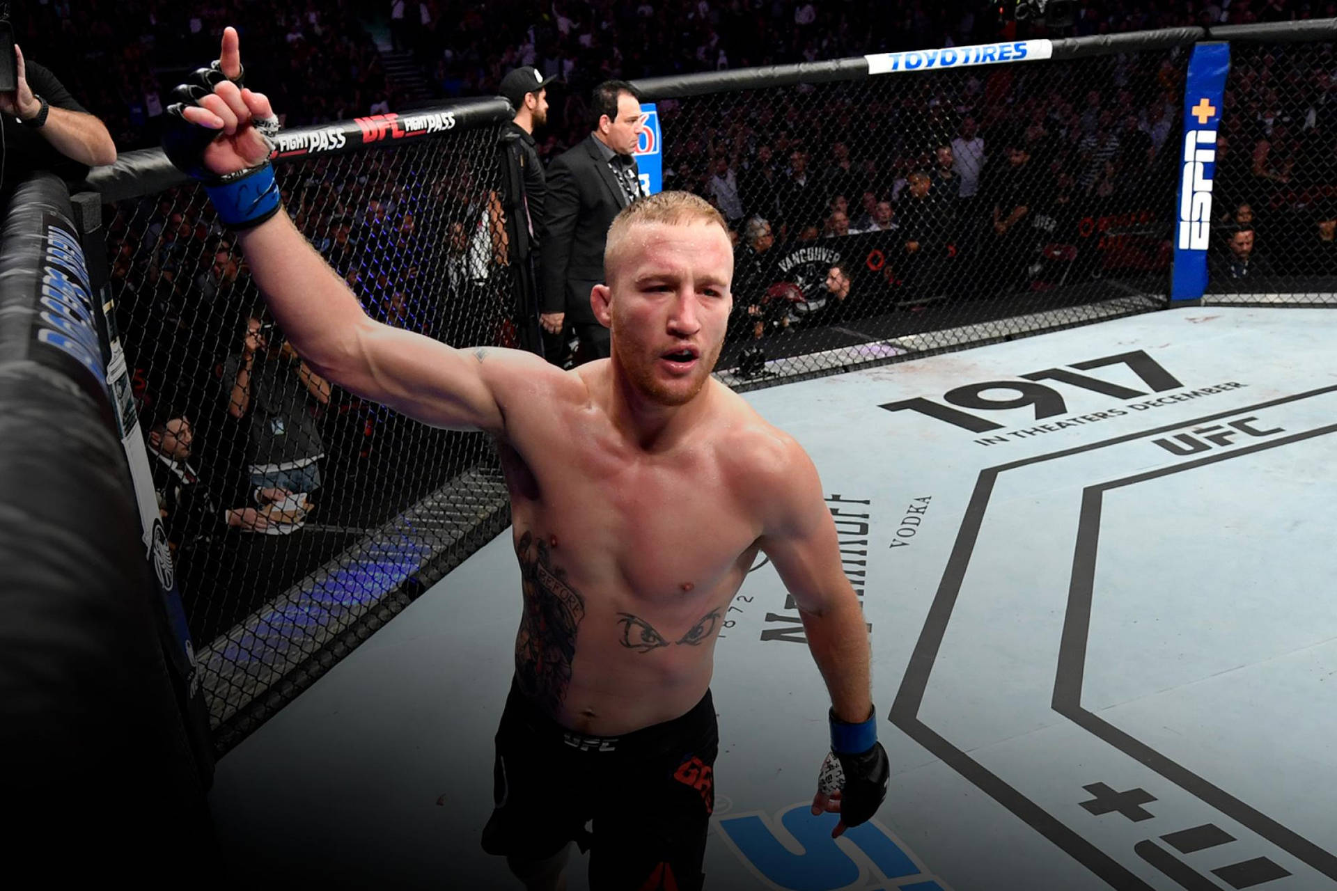 一位赤裸上身的MMA選手在UFC八角籠內高舉雙手慶祝勝利。