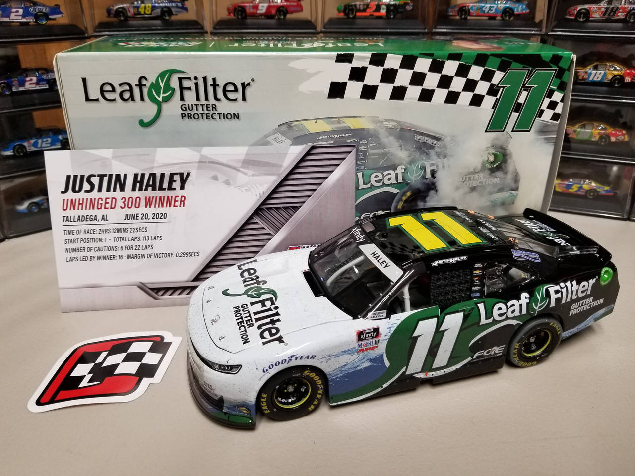 賈斯汀·黑利迷你賽車 壁紙 — 一個詳細的11 Leaf Filter NASCAR賽車模型放在架子上，旁邊是它的盒子和格子旗貼紙。