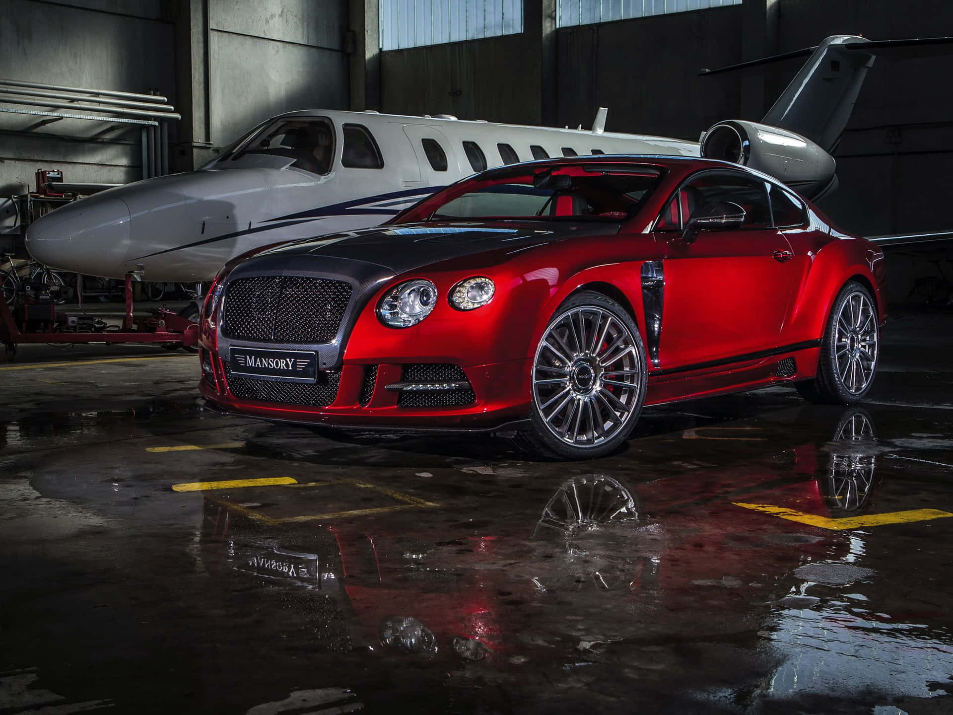 紅色Mansory Bentley跑車停在潮濕機庫中的私人飛機旁。