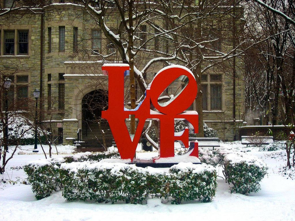 冬季校園環境中，被雪覆蓋的紅色LOVE雕塑。