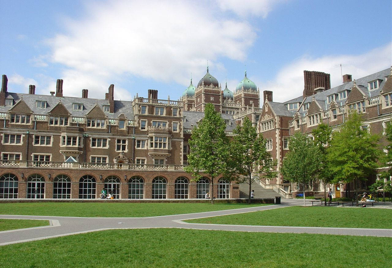 大學校園，擁有歷史磚砌建築和綠色草坪，在藍天下。