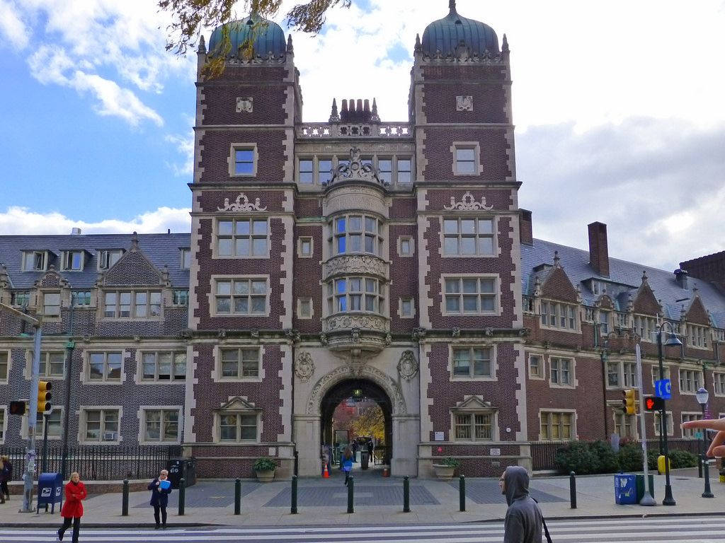 歷史磚砌建築，設有拱形大門和過馬路的人們。