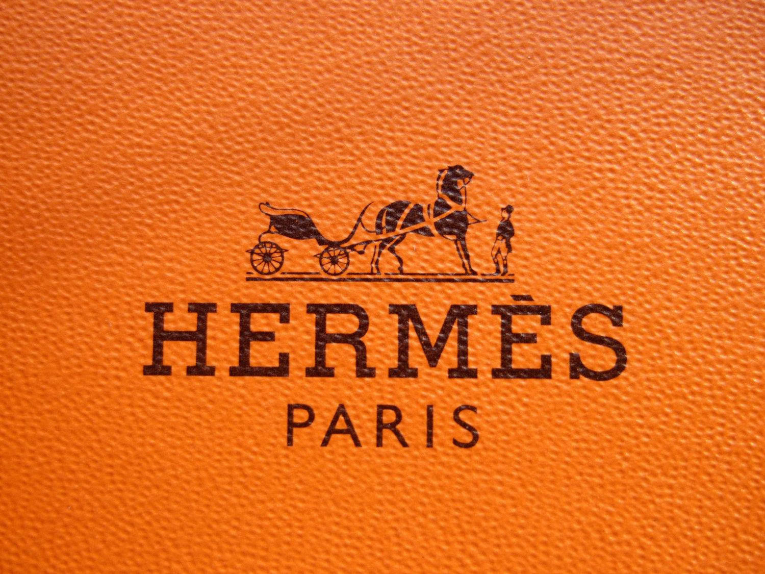 Hermès Paris 標誌在橙色紋理皮革上，帶有馬和馬車標誌。