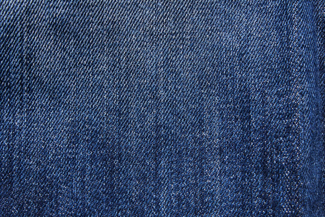 Denim Blue 桌布 壁紙 — 質感藍色牛仔布料的特寫，顯示詳細的編織紋理和微妙的褪色圖案。