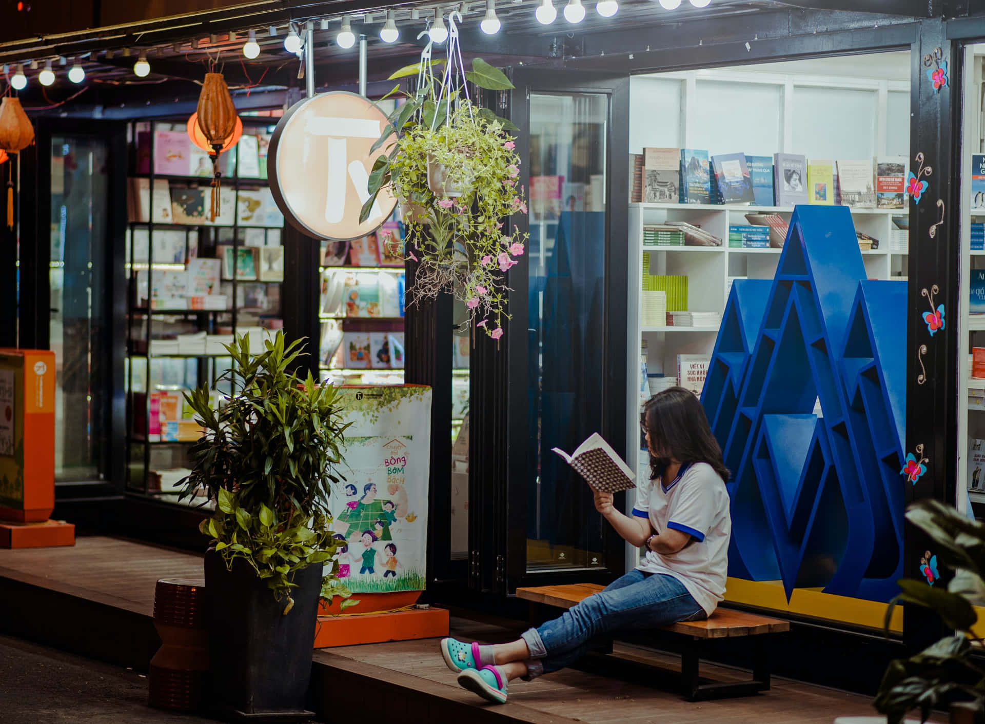 年輕女性晚上在書店外的長椅上閱讀
