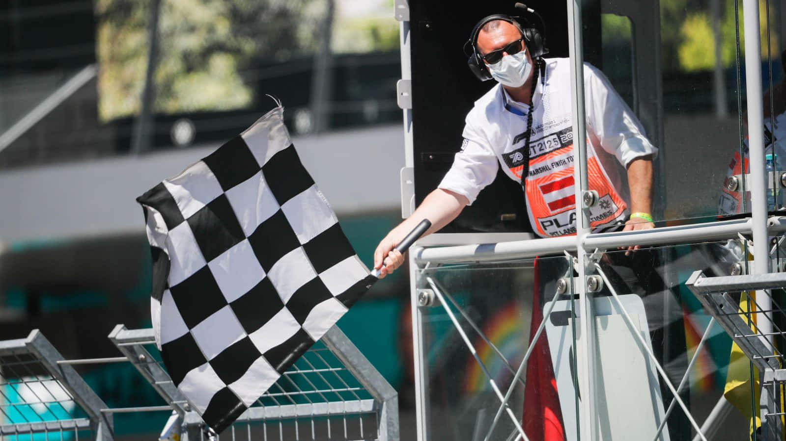 Chequered Flag 桌布 壁紙 — 賽事工作人員在晴朗的賽車活動中從塔樓揮動格仔旗。