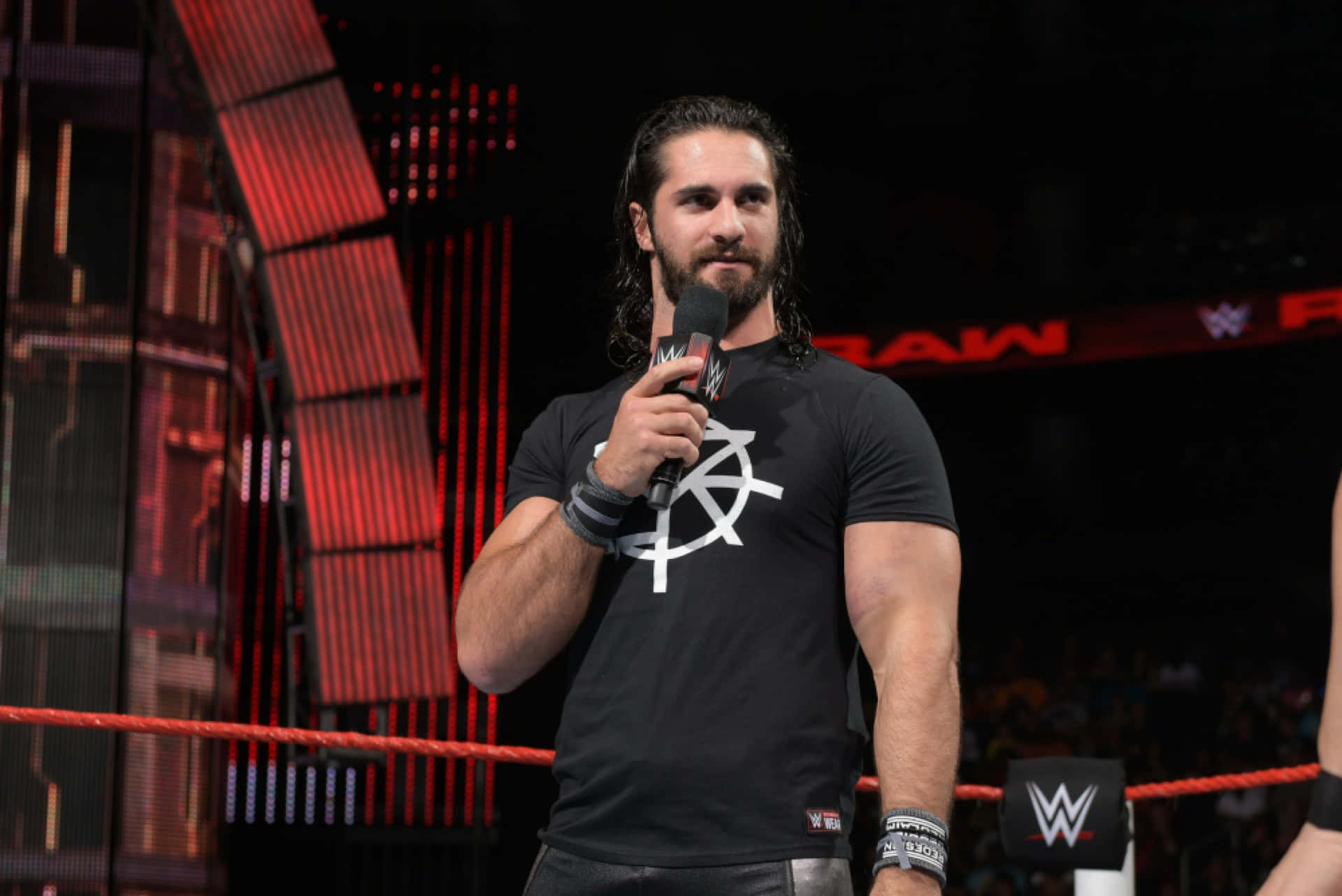 WWE摔角手Seth Rollins在摔角擂台上對著麥克風說話。