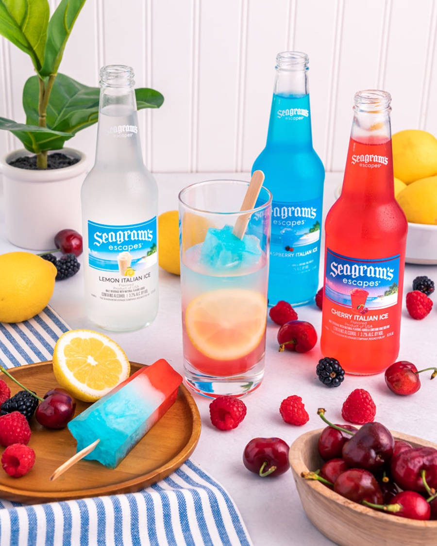 色彩繽紛的Seagram's Escapes飲品和冰棒，配以新鮮水果，放在條紋桌布上。