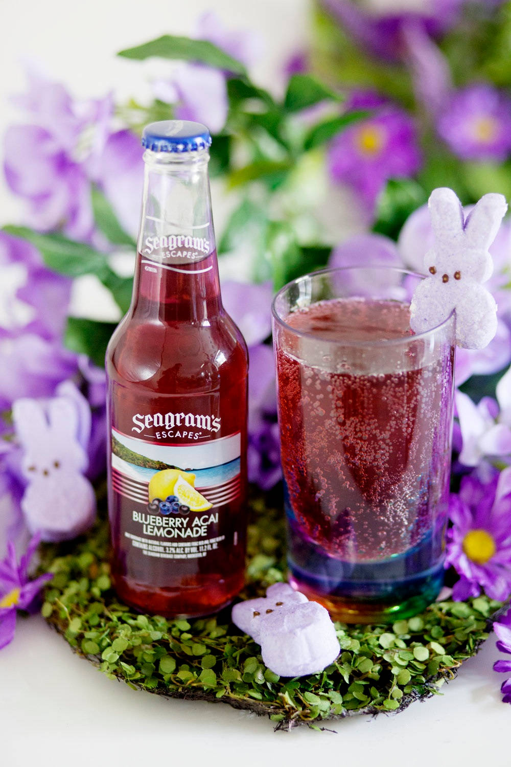 Seagram's Blueberry Acai Lemonade 瓶子和杯子，搭配兔子糖果和紫色花朵。