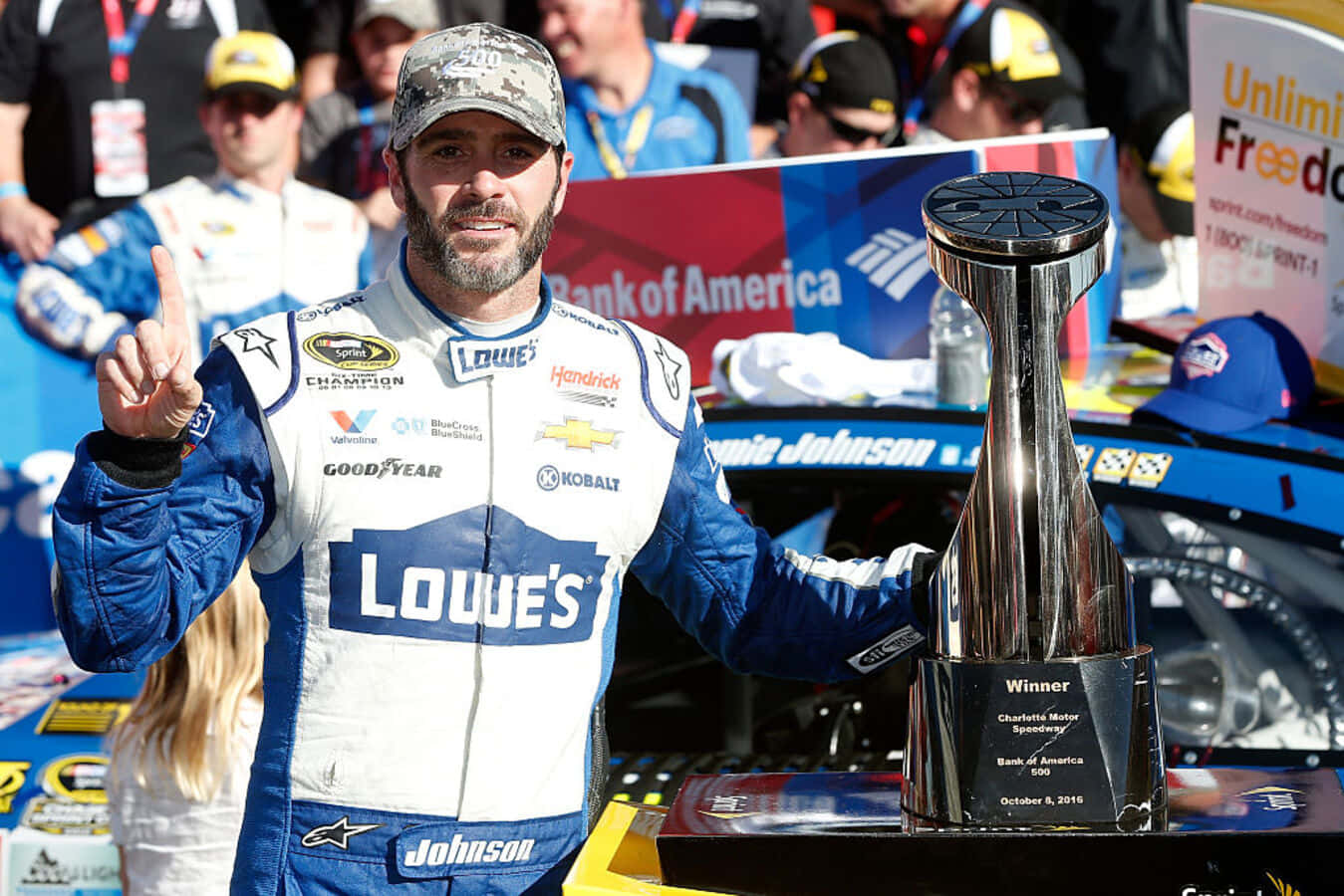 Jimmie Johnson 桌布 壁紙 — 賽車手 Jamie Johnson 在夏洛特賽車場陽光明媚的一天，手持閃閃發光的獎盃慶祝勝利。