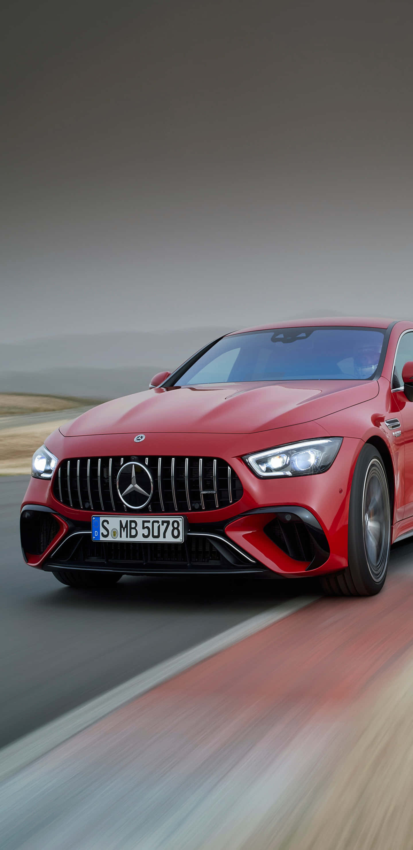 賽車紅梅賽德斯-奔馳 AMG GT-R 背景 壁紙 — 一輛鮮紅色的Mercedes-AMG GT R在朦朧的天空下，沿著模糊的沙漠道路飛馳。