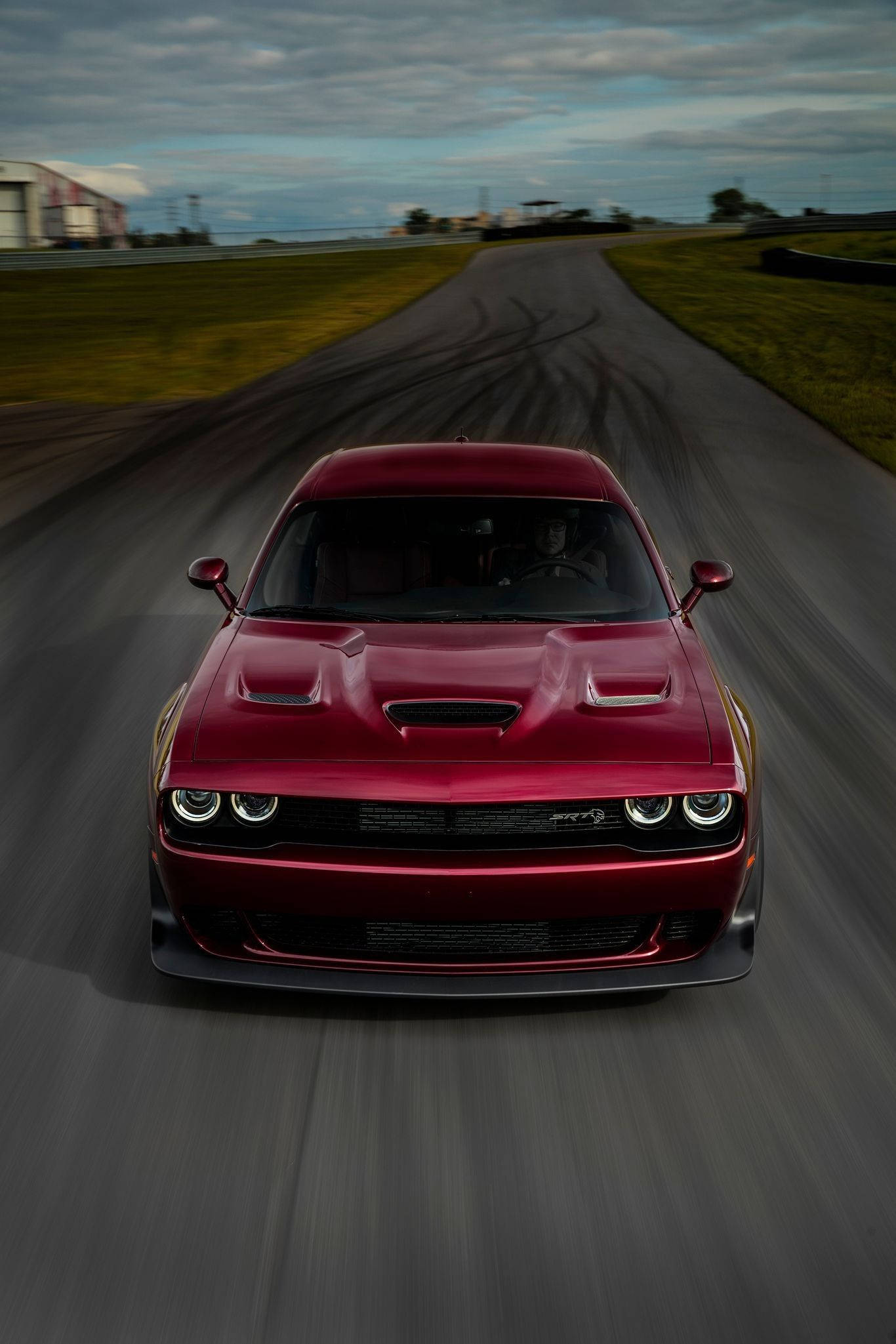 賽道上孤立的Octane紅色道奇挑戰者Demon 壁紙 — 一輛紅色 Dodge Challenger SRT Hellcat 在賽道上高速行駛，在陰天留下輪胎痕跡。