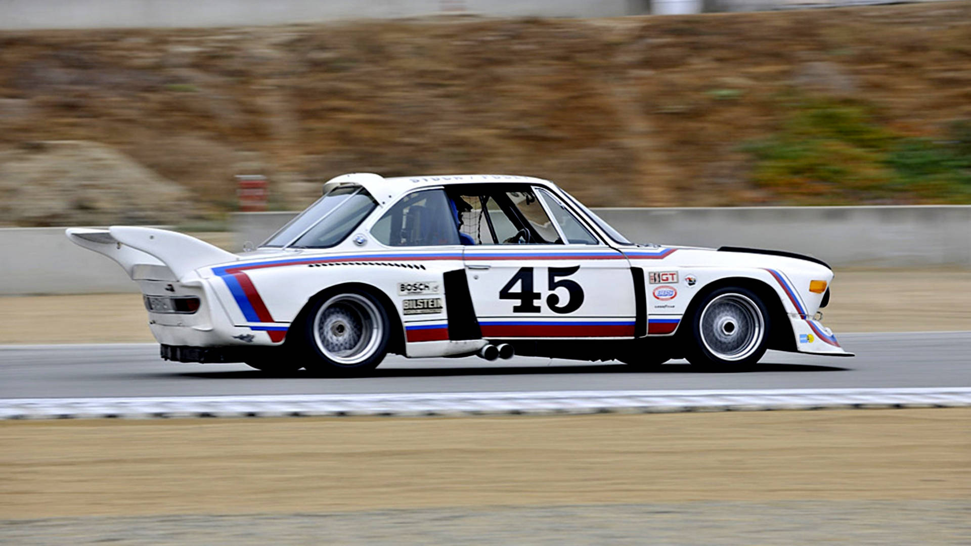白色寶馬賽車編號45在賽道上疾馳，帶有動態模糊。