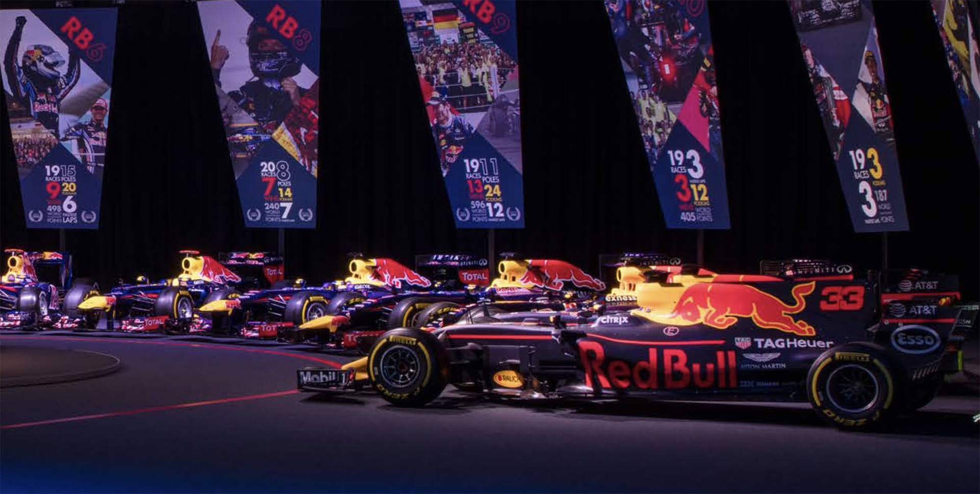 Red Bull F1 賽車在舞台上展示，背景有冠軍旗幟。