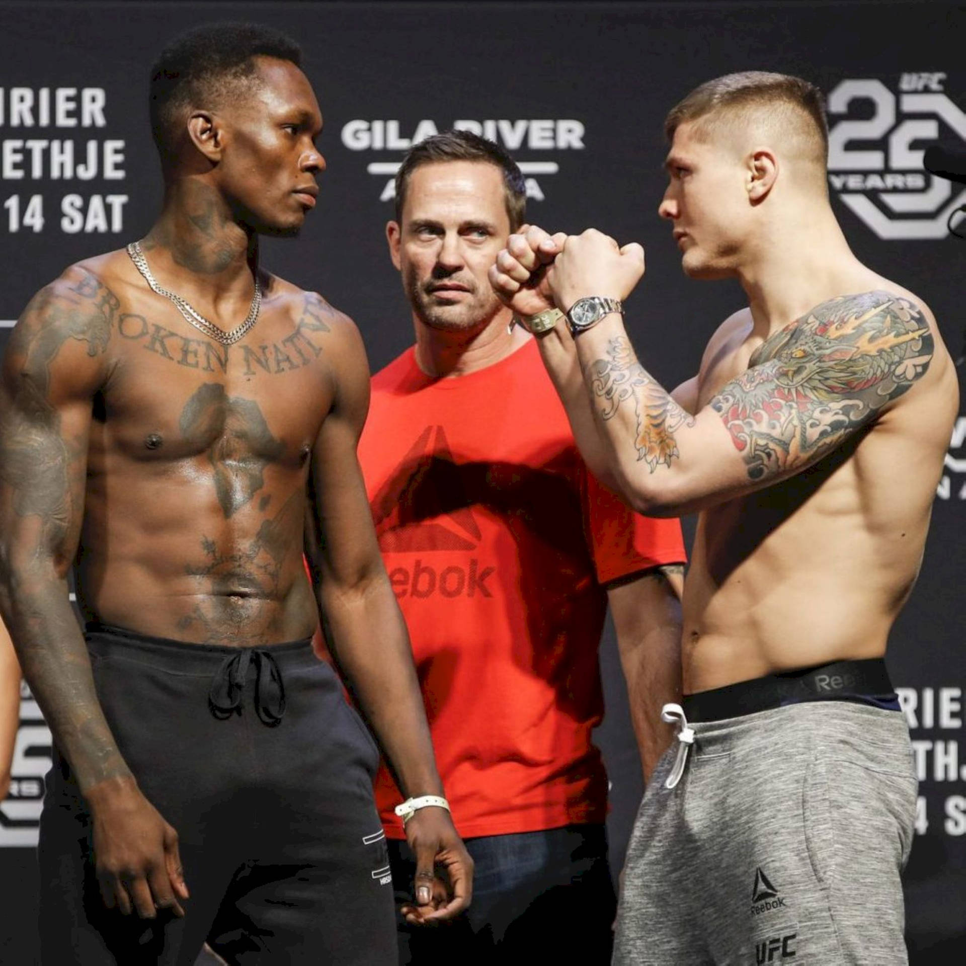 兩名男性MMA拳手在UFC過磅活動中鎖拳，裁判在旁觀看。