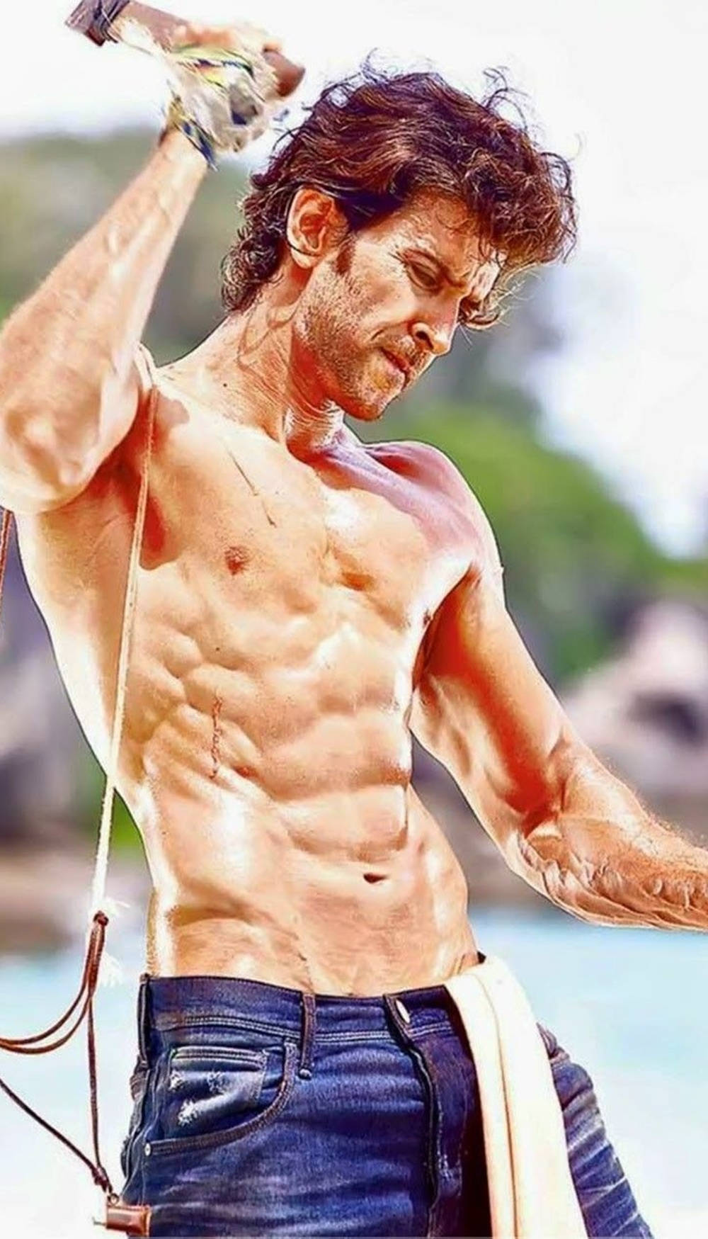 一個肌肉男在海灘上將水倒在腹部上。