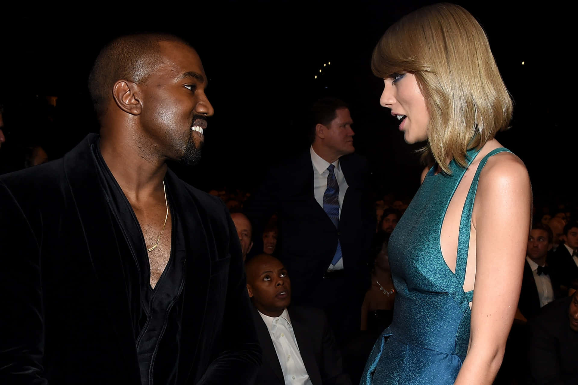 Kanye West 和 Taylor Swift 在黑暗的活動環境中互相微笑。