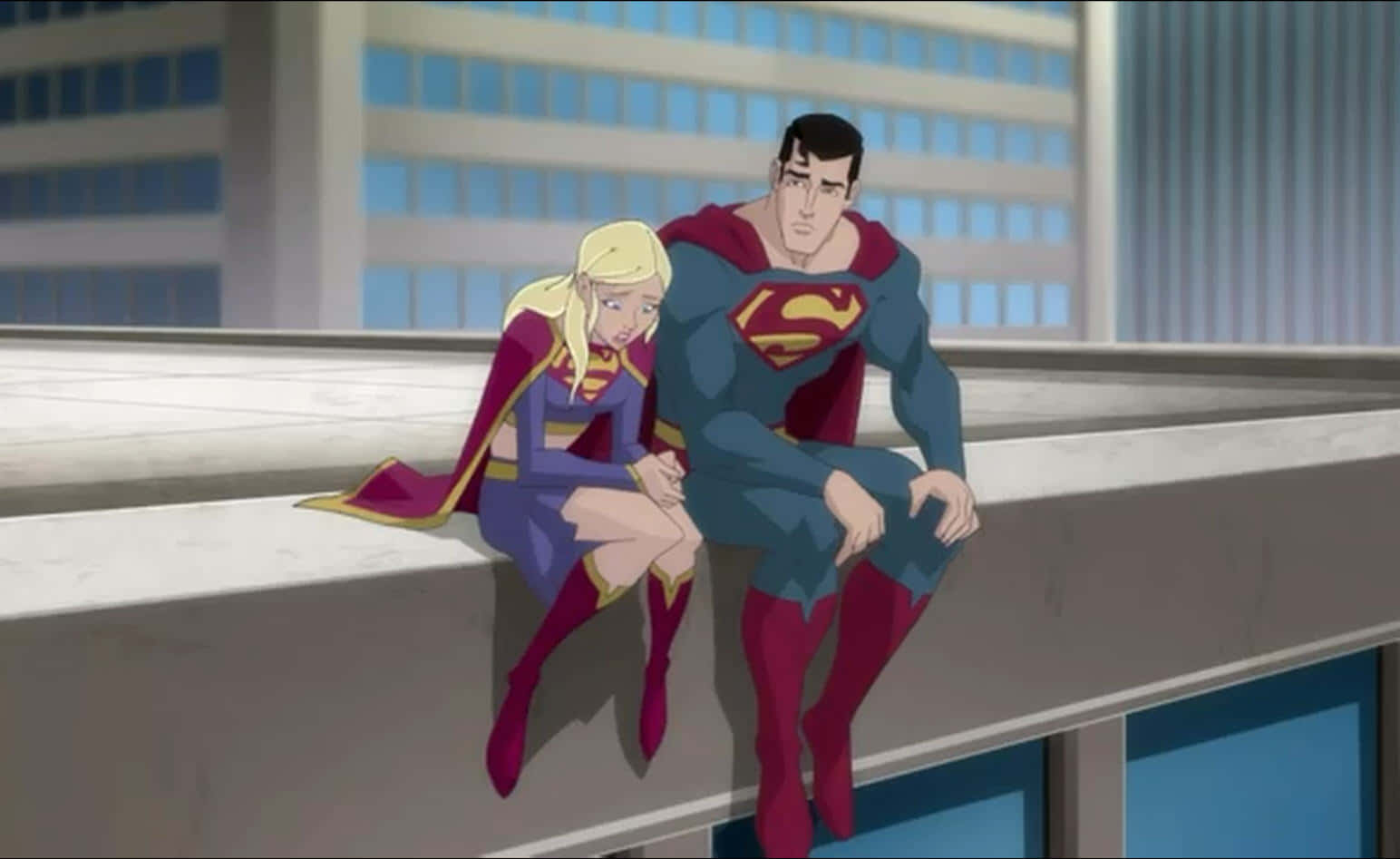 Superman Unbound 桌布 壁紙 — 超人和超級女孩並排坐在城市屋頂邊緣，背景是高聳的玻璃建築。