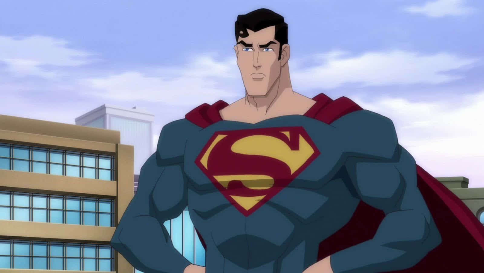 Superman Unbound 桌布 壁紙 — 超人自信地站立，身穿標誌性藍色戰衣配紅色斗篷，背景是陰雲密布的城市天際線。