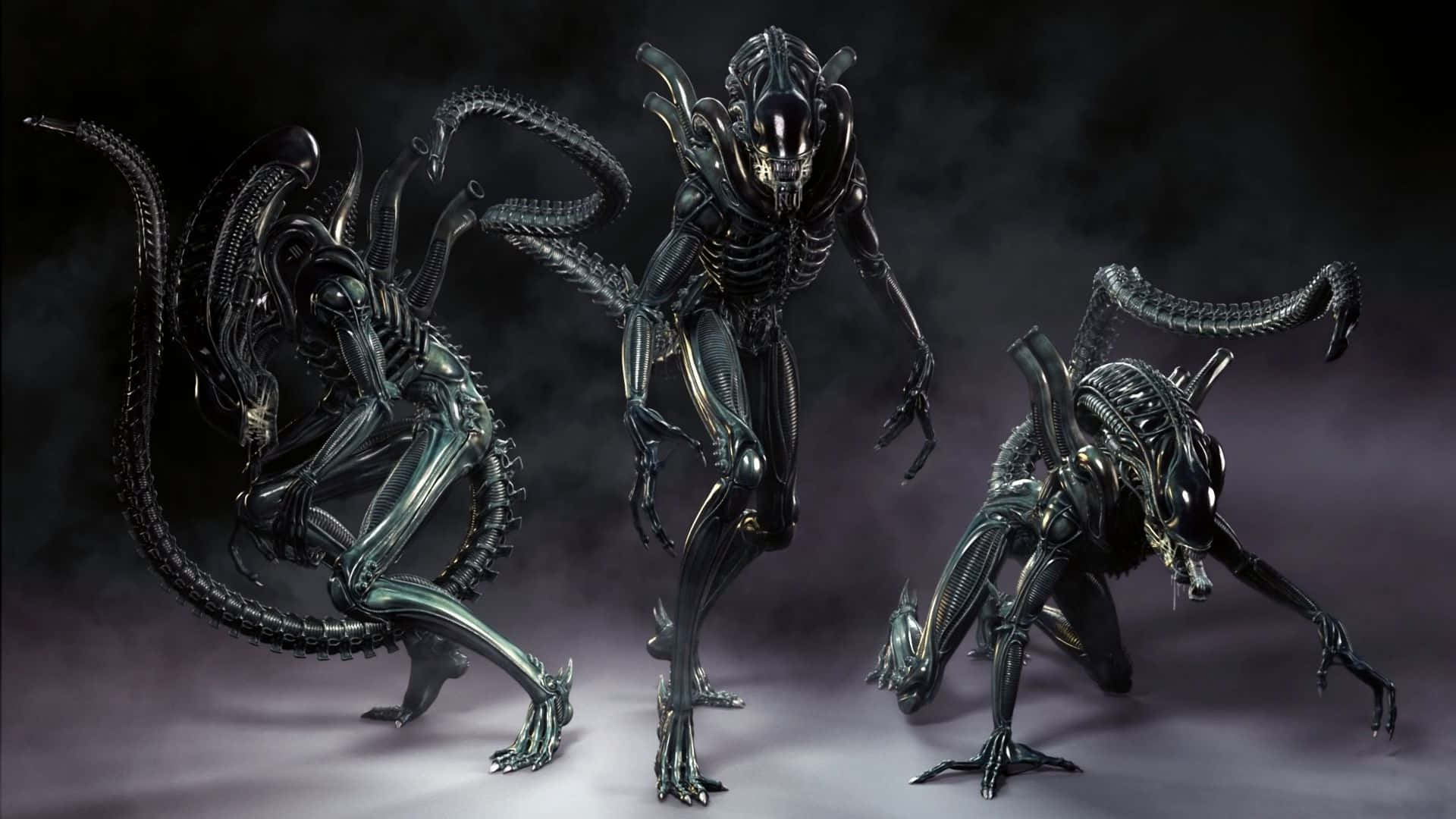 超凡異星生物 壁紙 — 三個生物機械外星生物，頭骨細長，尾巴像鞭子，在煙霧瀰漫的黑暗工作室中威嚇地站立。